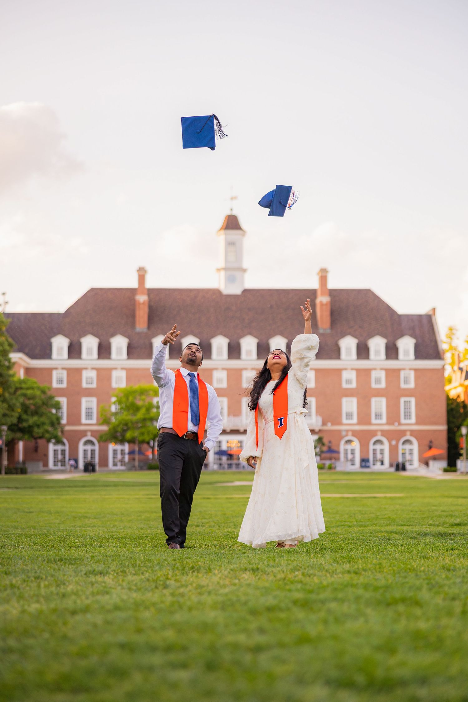 Graduating couple tossing their caps in front of the Illini Union at the University of Illinois