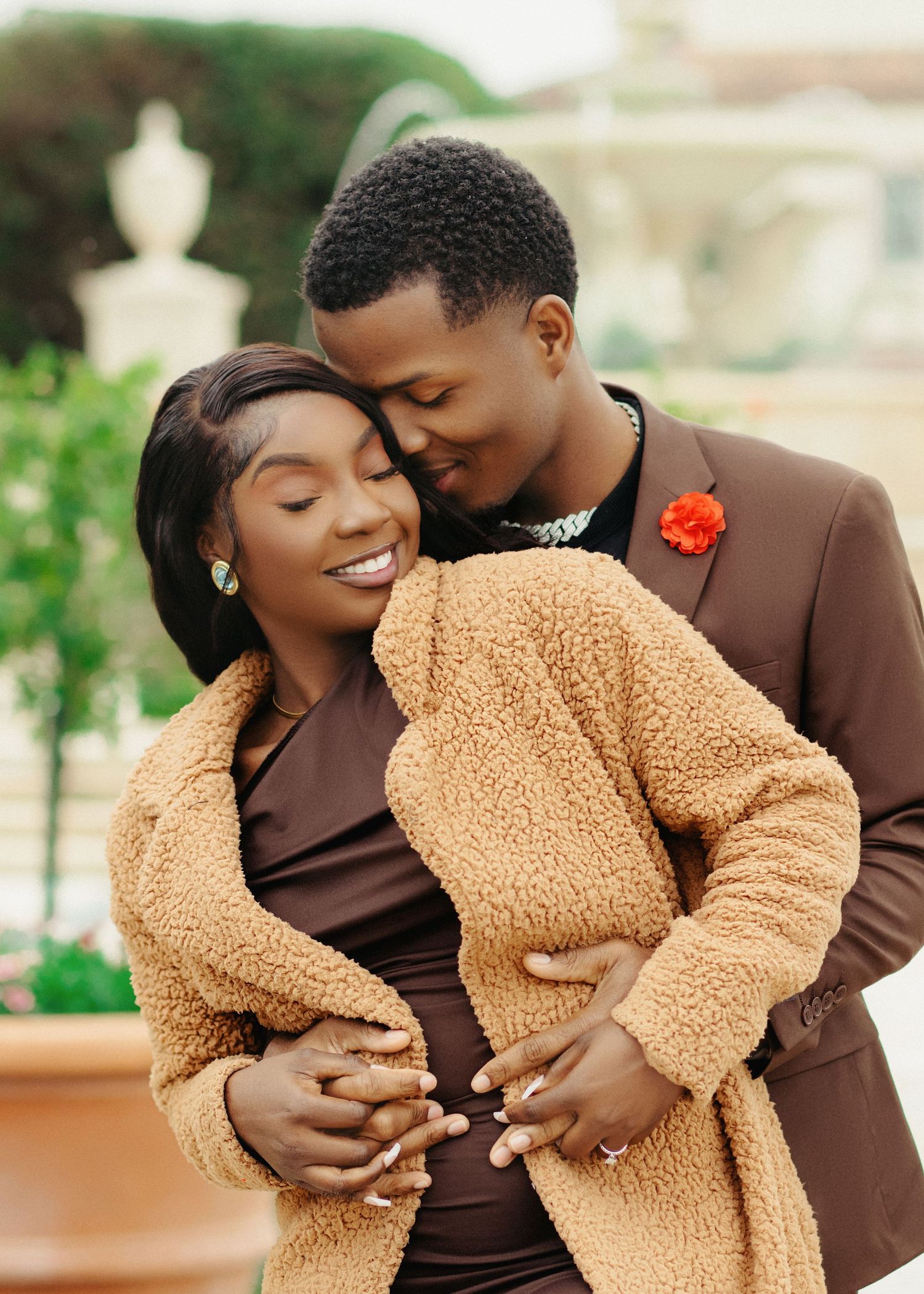 Romantic couple embraces in matching brown and beige outfits during outdoor photoshoot.