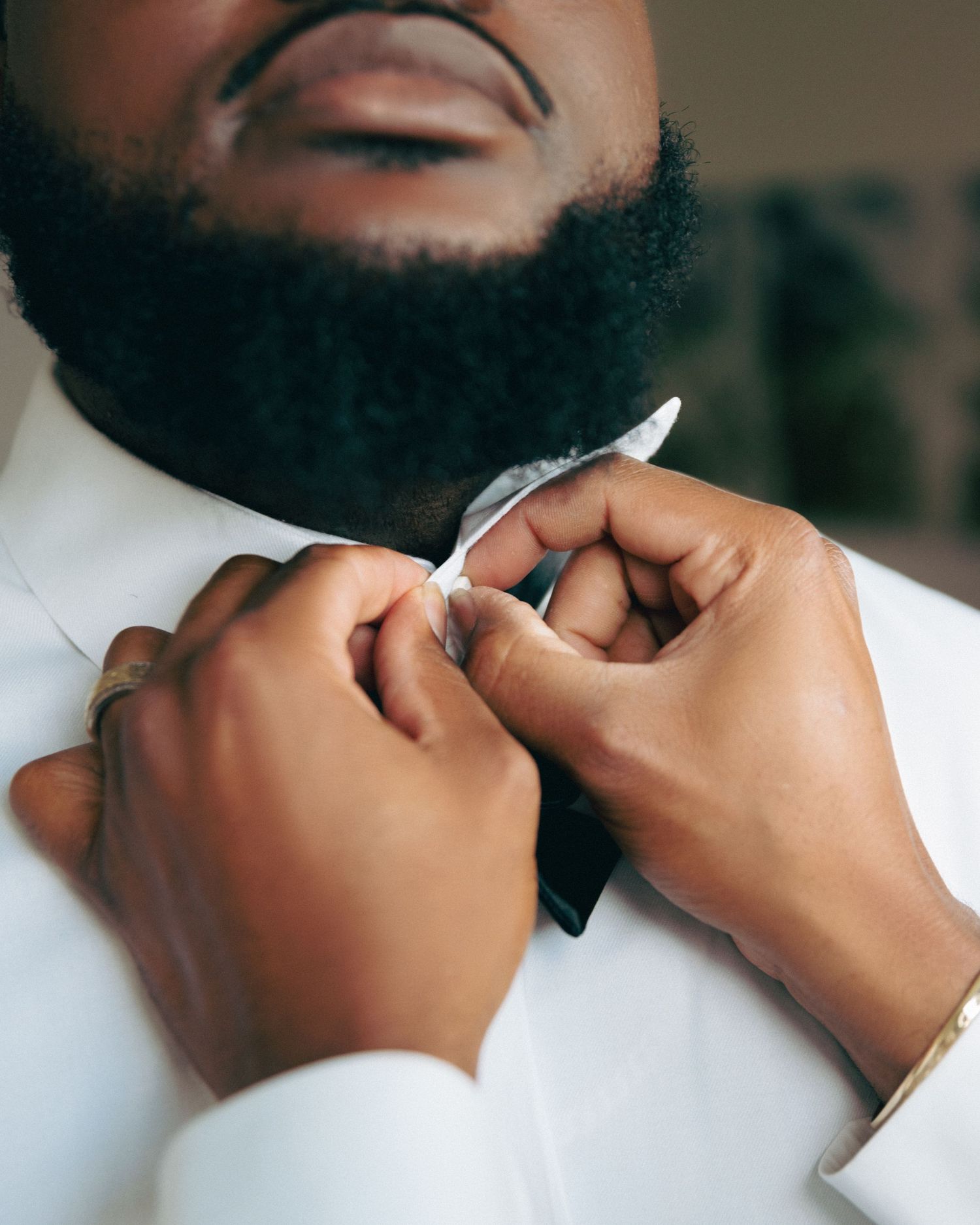 Close-up shot of hands adjusting a black bowtie on a white shirt.