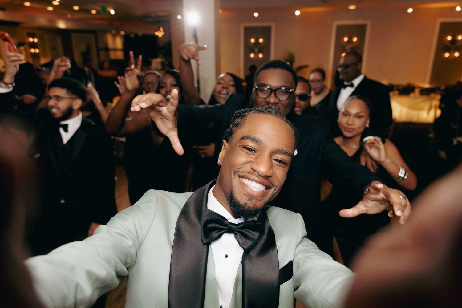 Joyful wedding celebration with guests dancing and celebrating in a warmly lit reception venue.