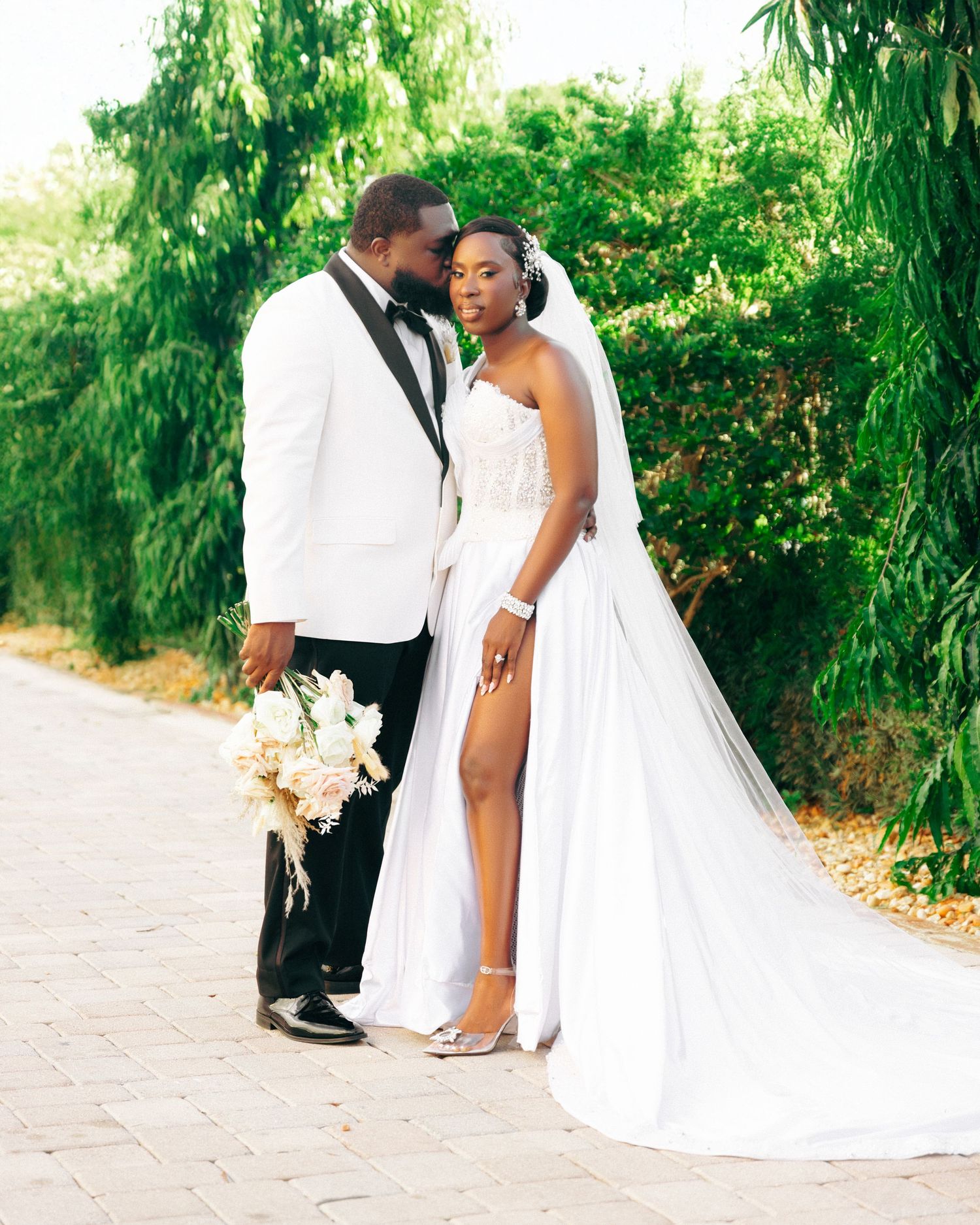 Elegant wedding couple poses in a lush garden setting with greenery and flowers.