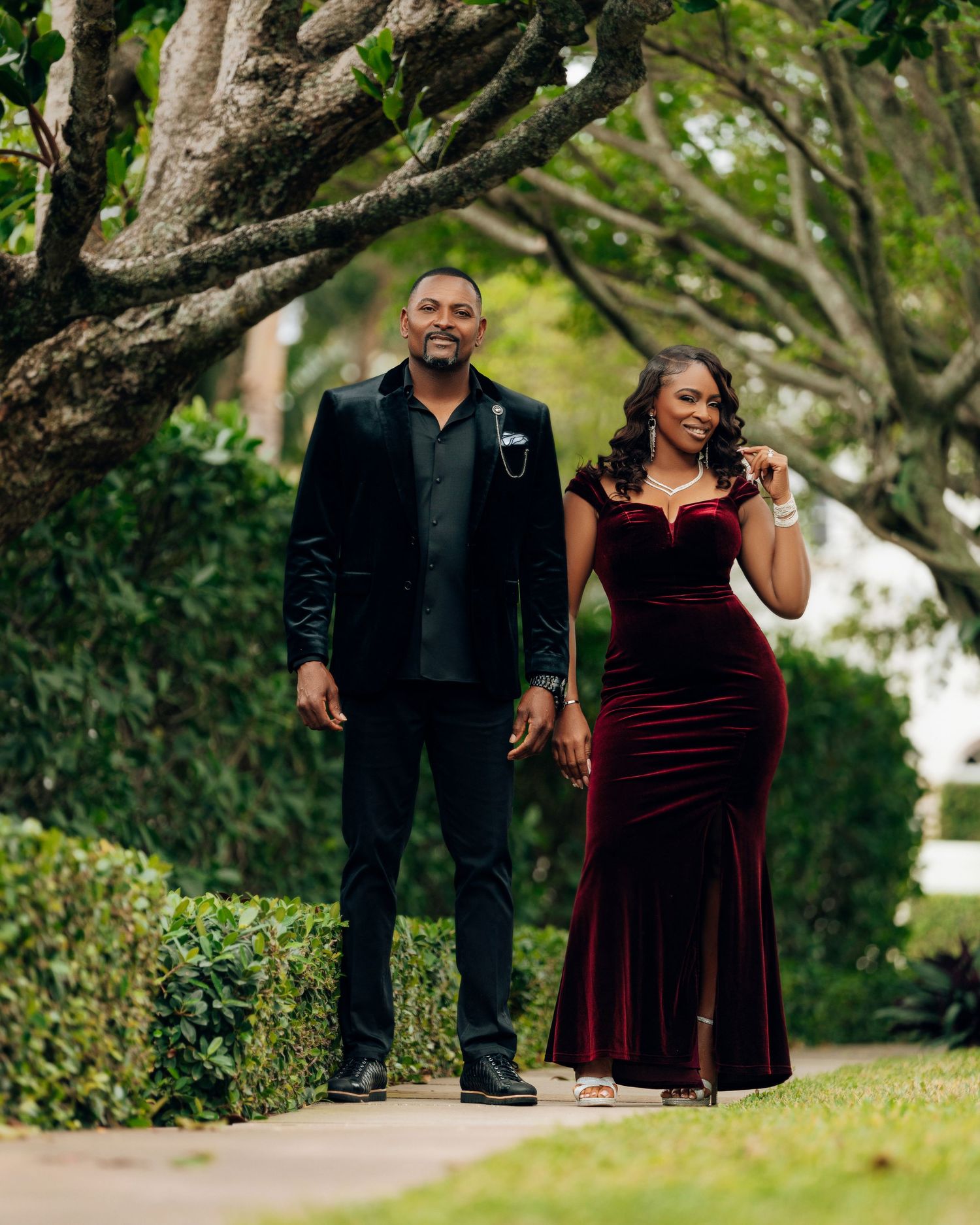 Couple walking together on a tree-lined path during their engagement session.