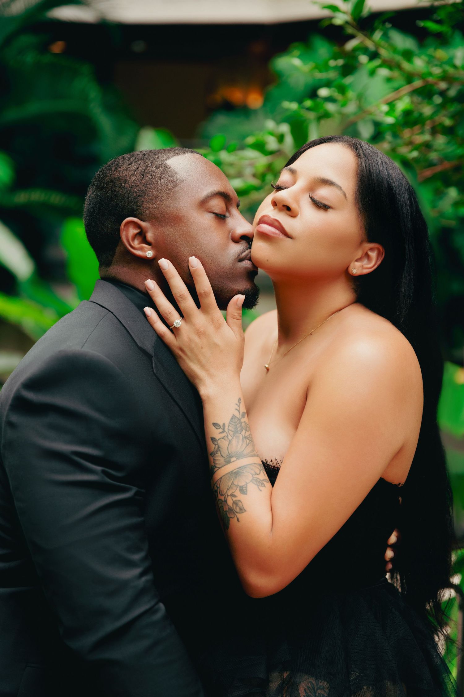 Romantic couple in formal wear embracing in garden setting.