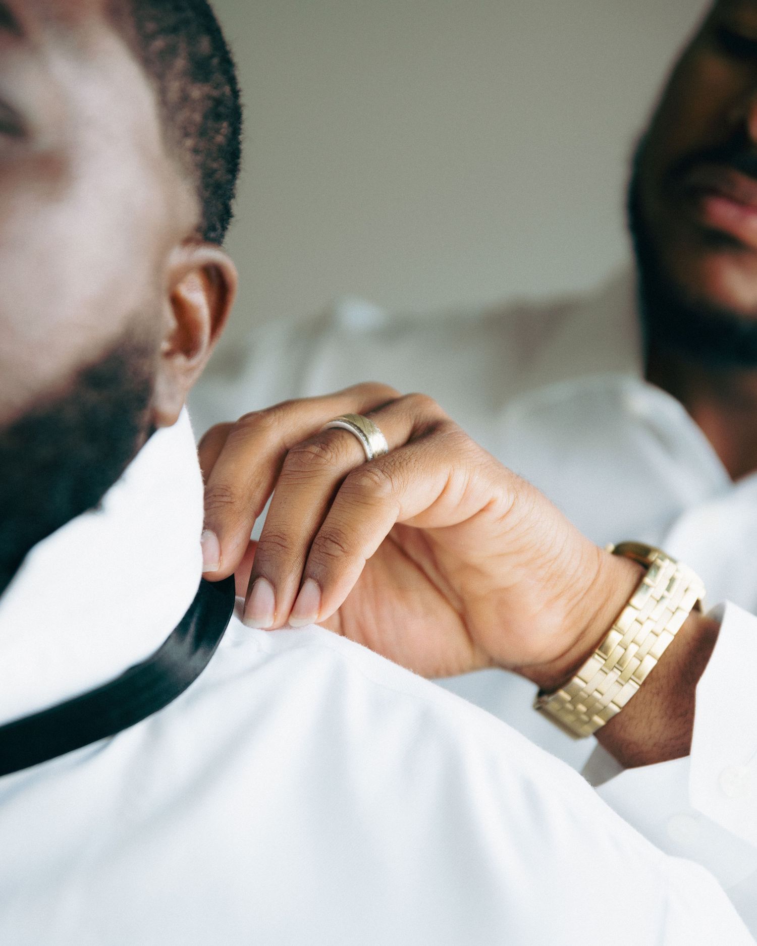 Close-up of hands with wedding rings and a gold watch.