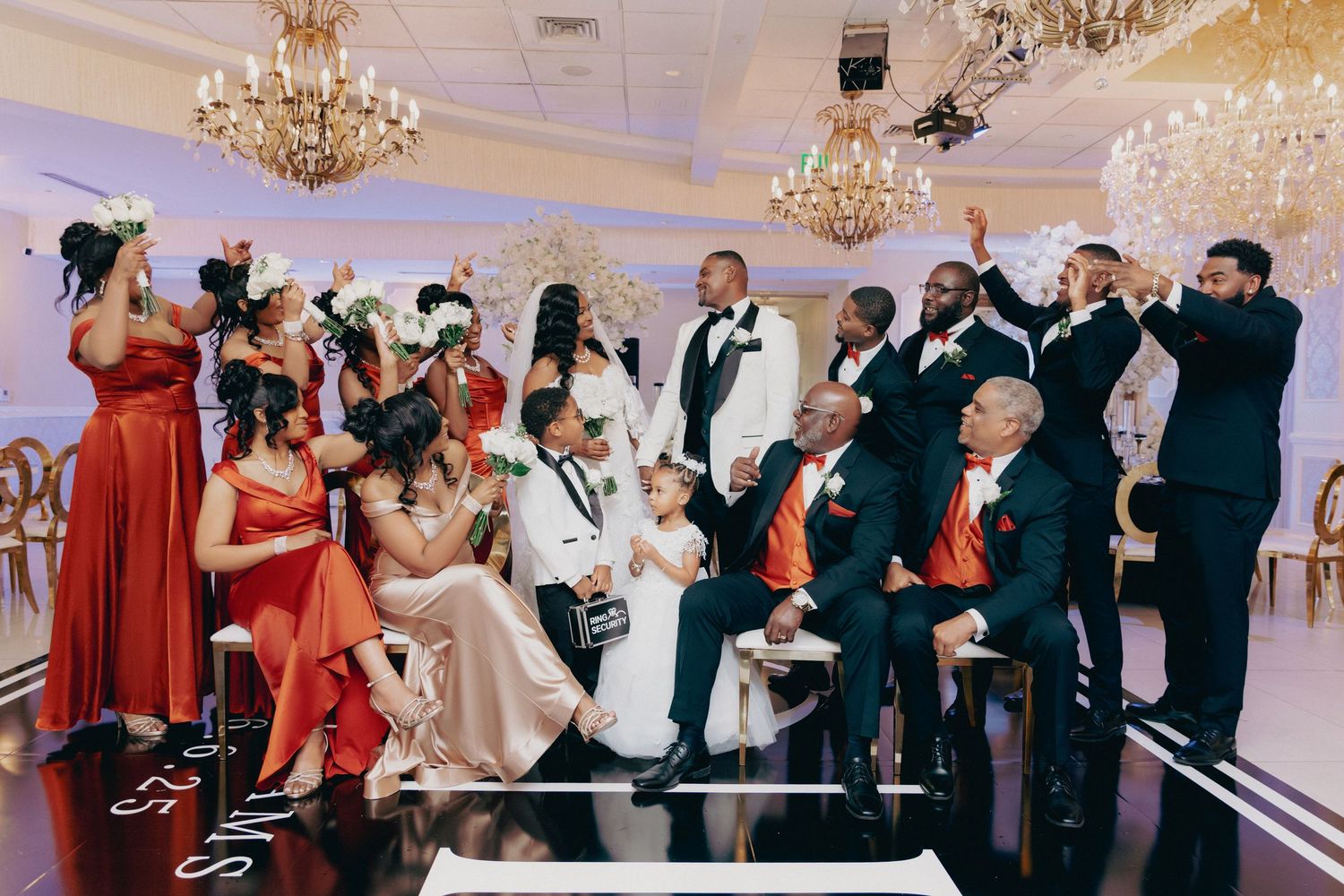 Wedding reception celebration with guests dancing under crystal chandeliers.