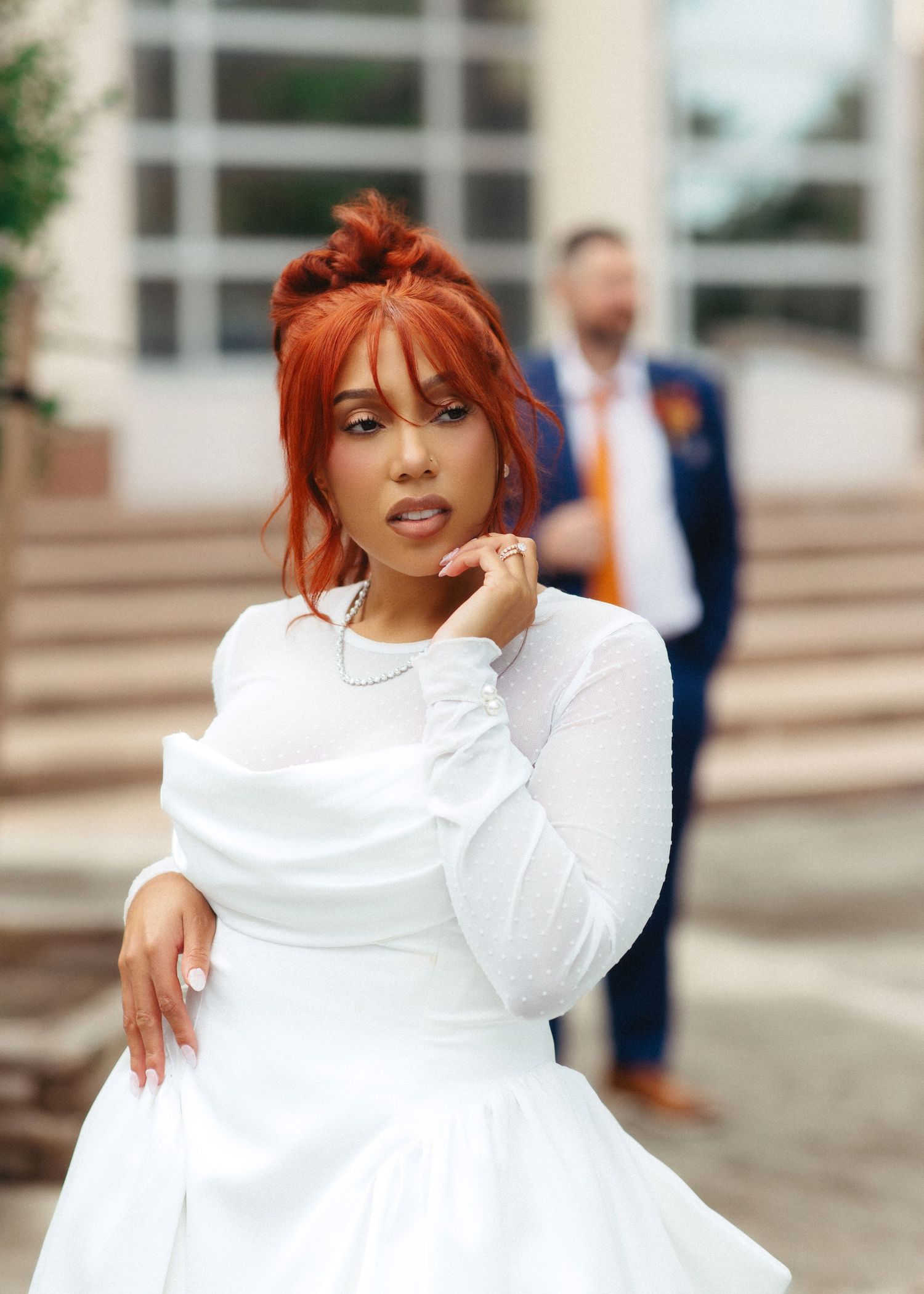 A person with vibrant red hair and a white turtleneck sweater poses confidently in a series of outdoor portraits.
