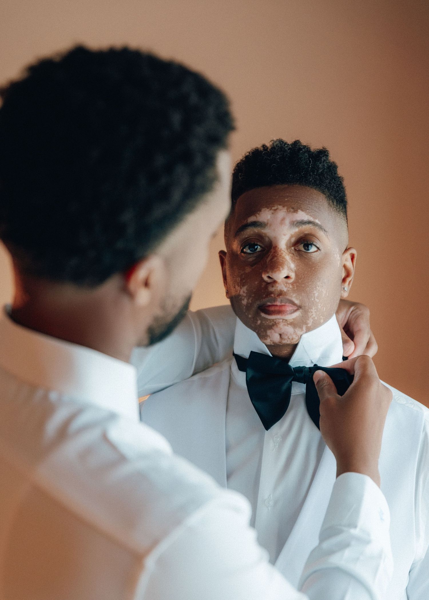 A series of portrait shots showing someone adjusting their bowtie and getting ready in formal attire.