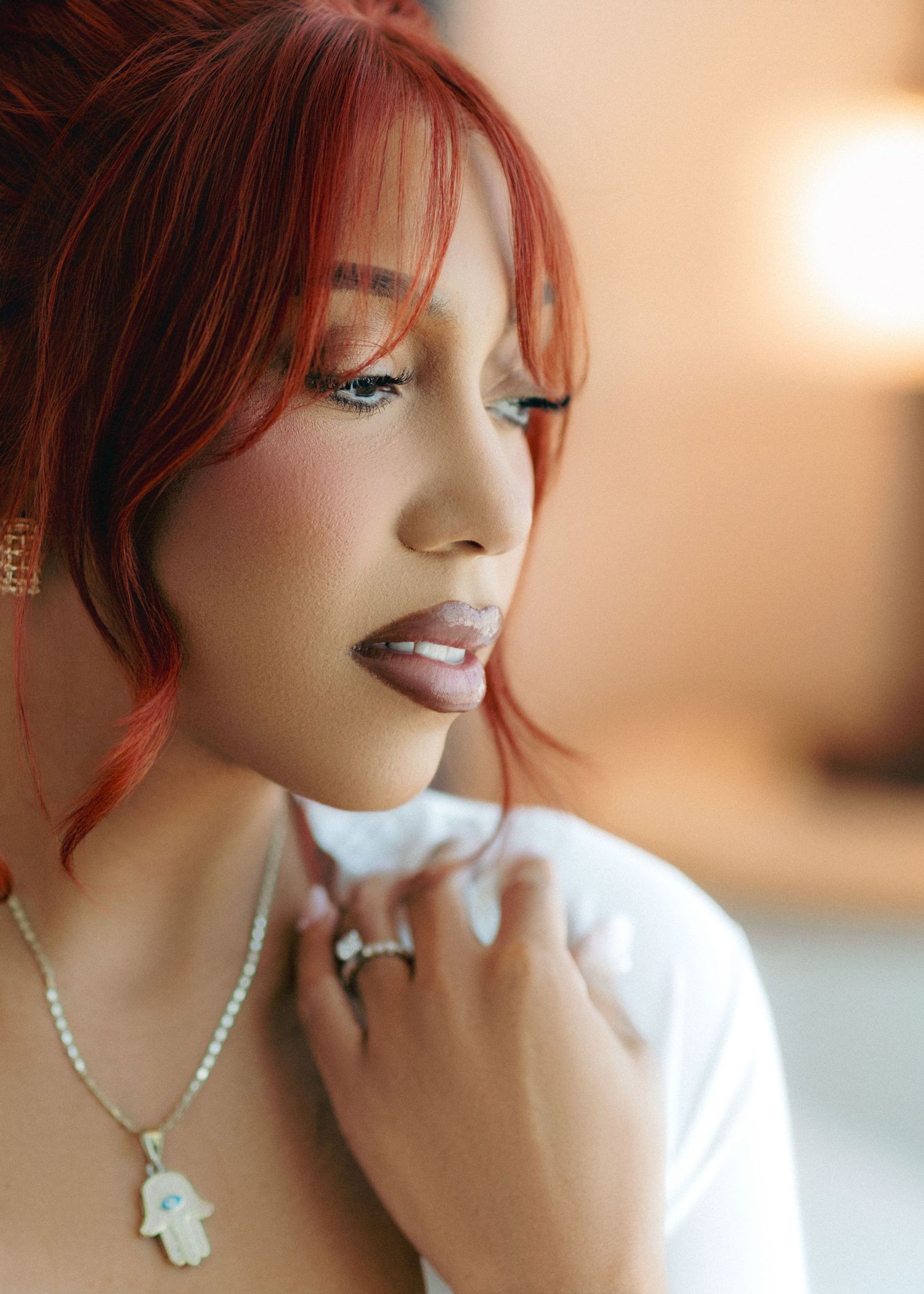 A series of five soft-lit portraits showing a person with red hair and pearl necklace in different poses against a warm background.