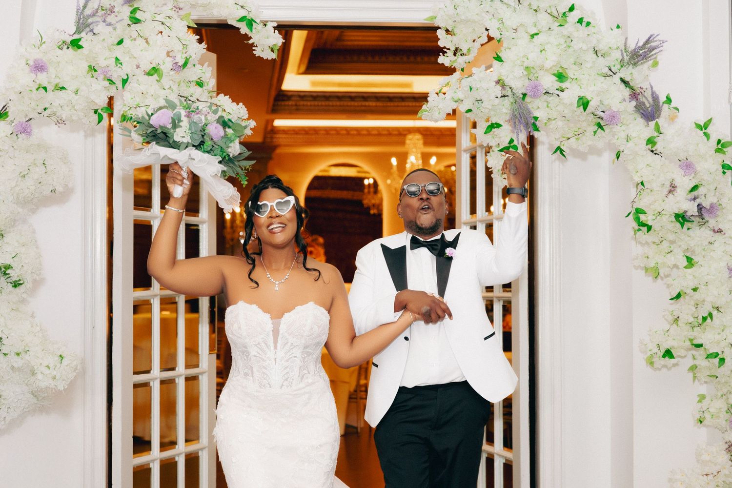 Wedding ceremony space decorated with white floral arches and elegant drapery.
