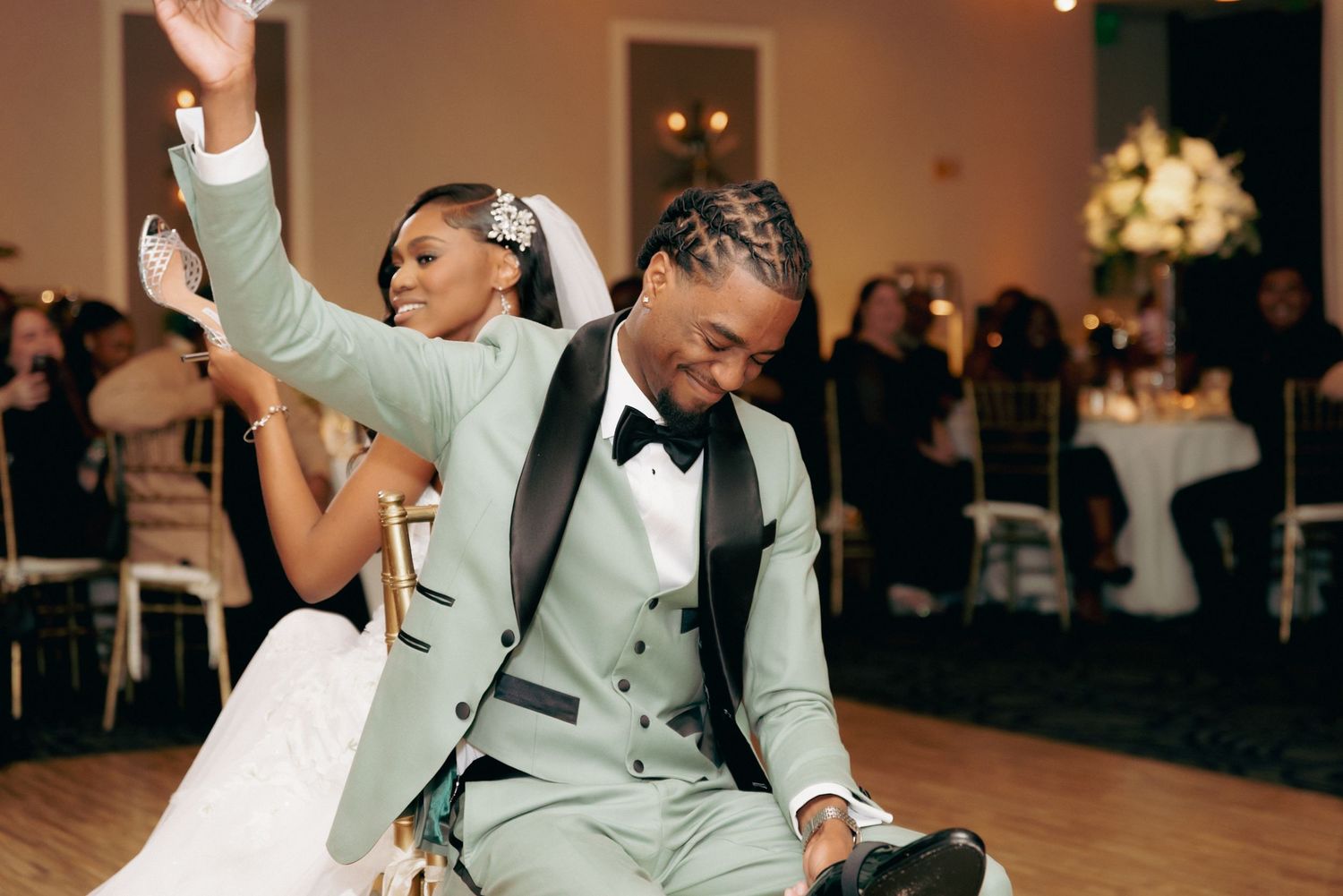 Guests dancing and celebrating at a lively wedding reception with dim lighting and elegant decor.
