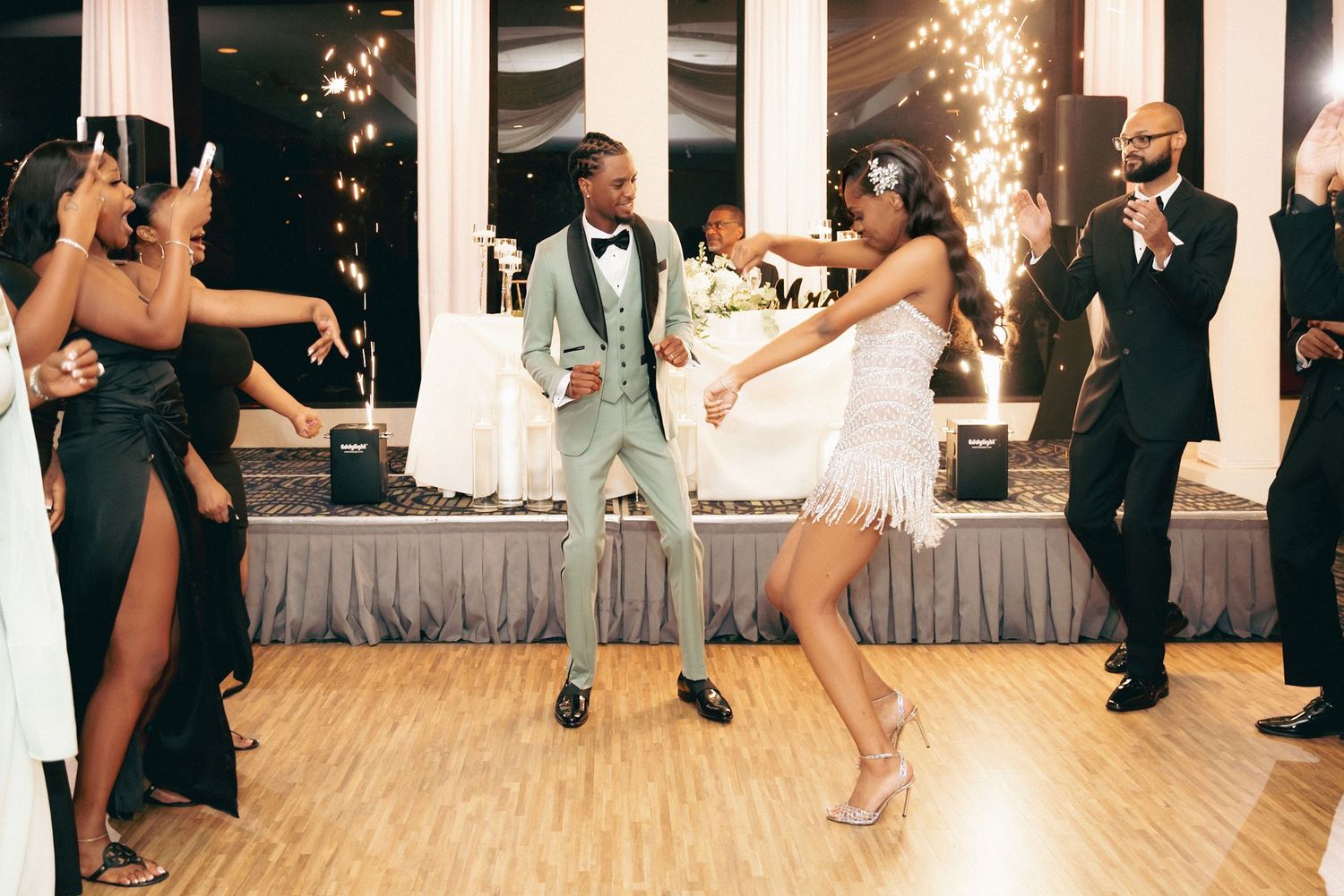 Wedding reception dance floor scene with sparklers as couple and guests celebrate with energetic moves.