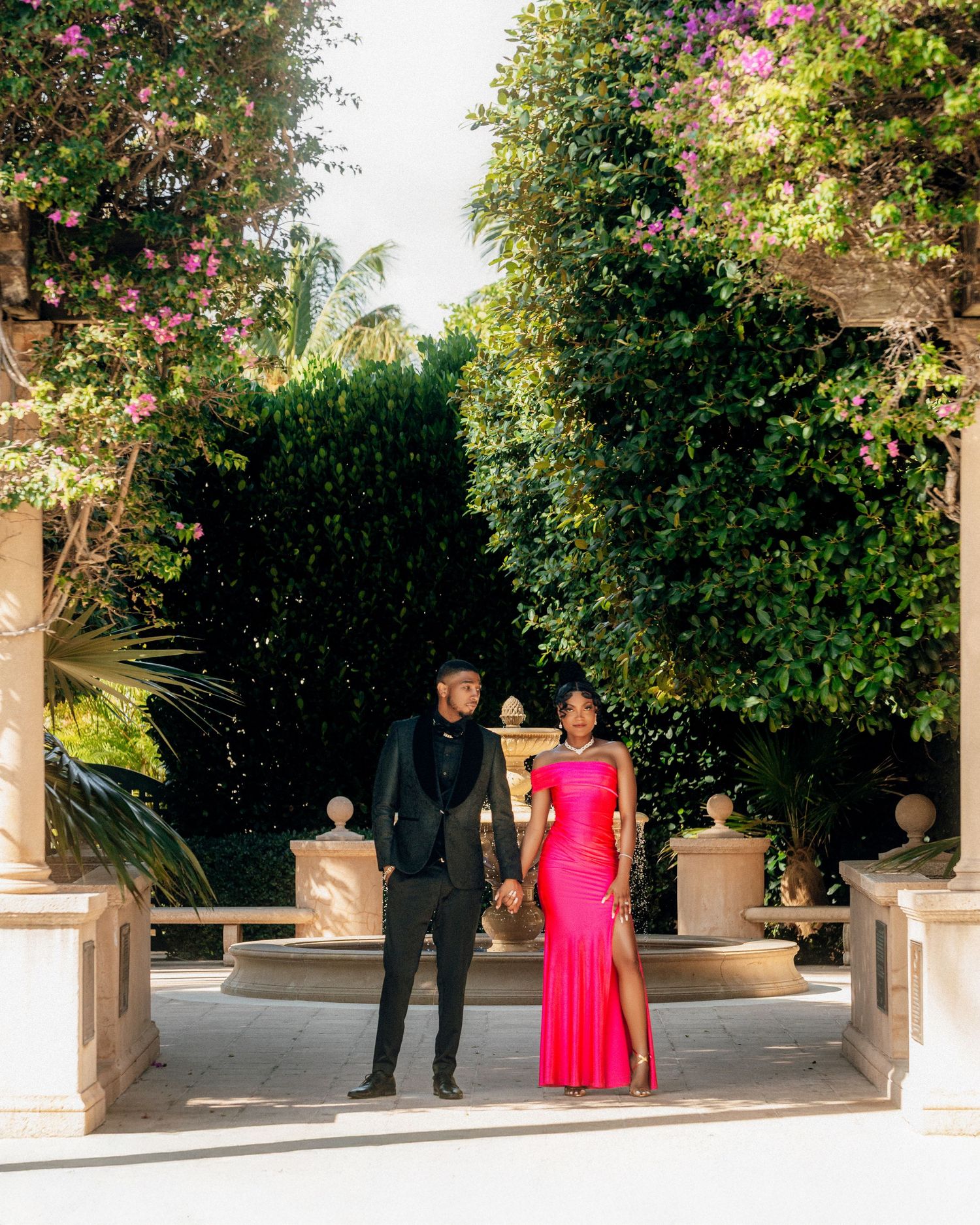 Elegant wedding party photographed in outdoor courtyard with lush landscaping.