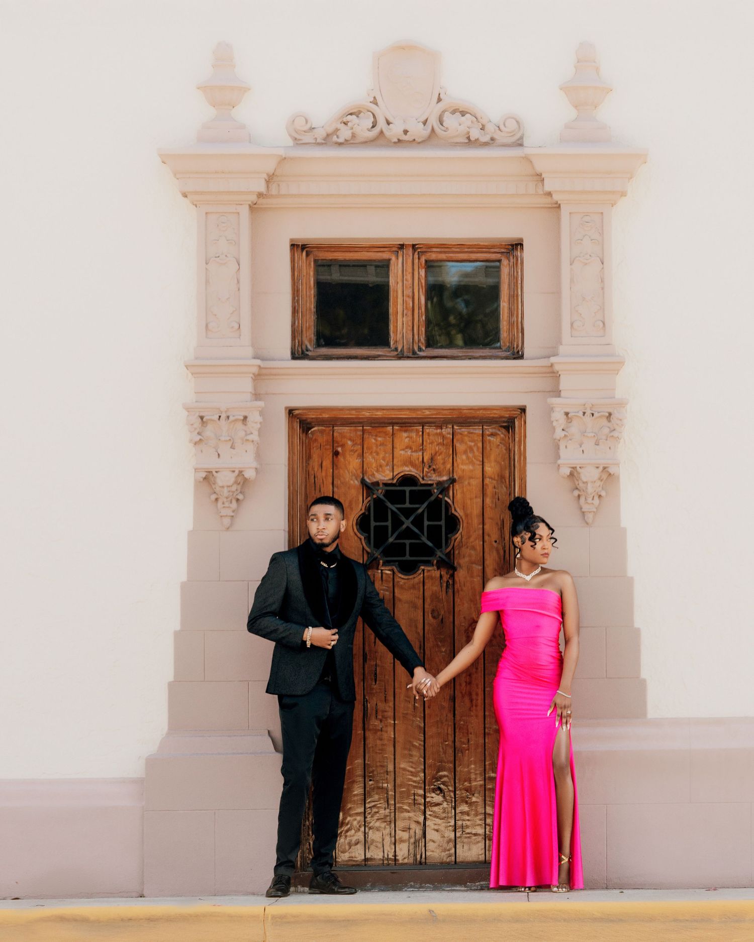 Wedding party poses in front of ornate wooden door with classic architectural details.