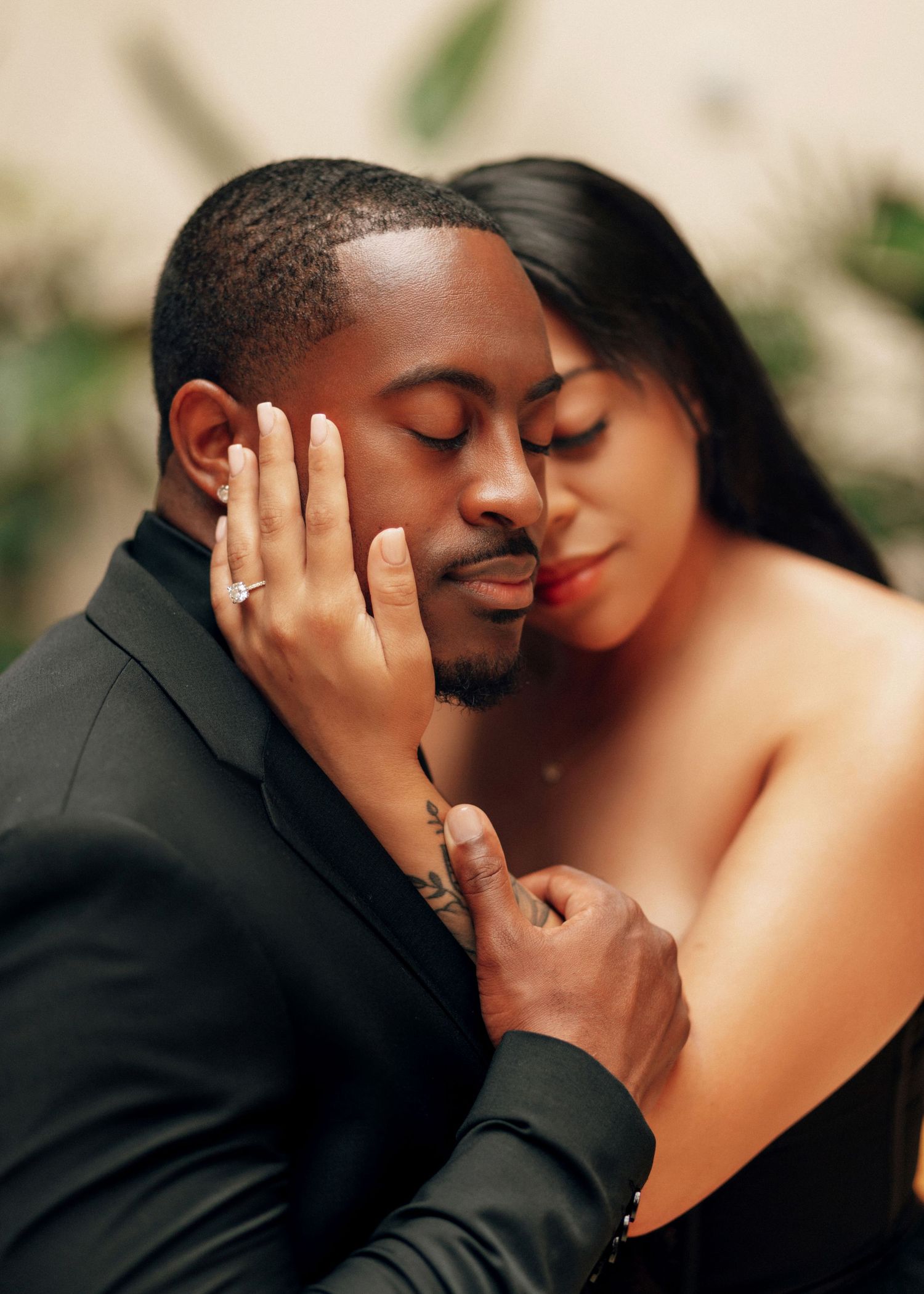 Intimate couple sharing tender moments in formal attire against neutral background.