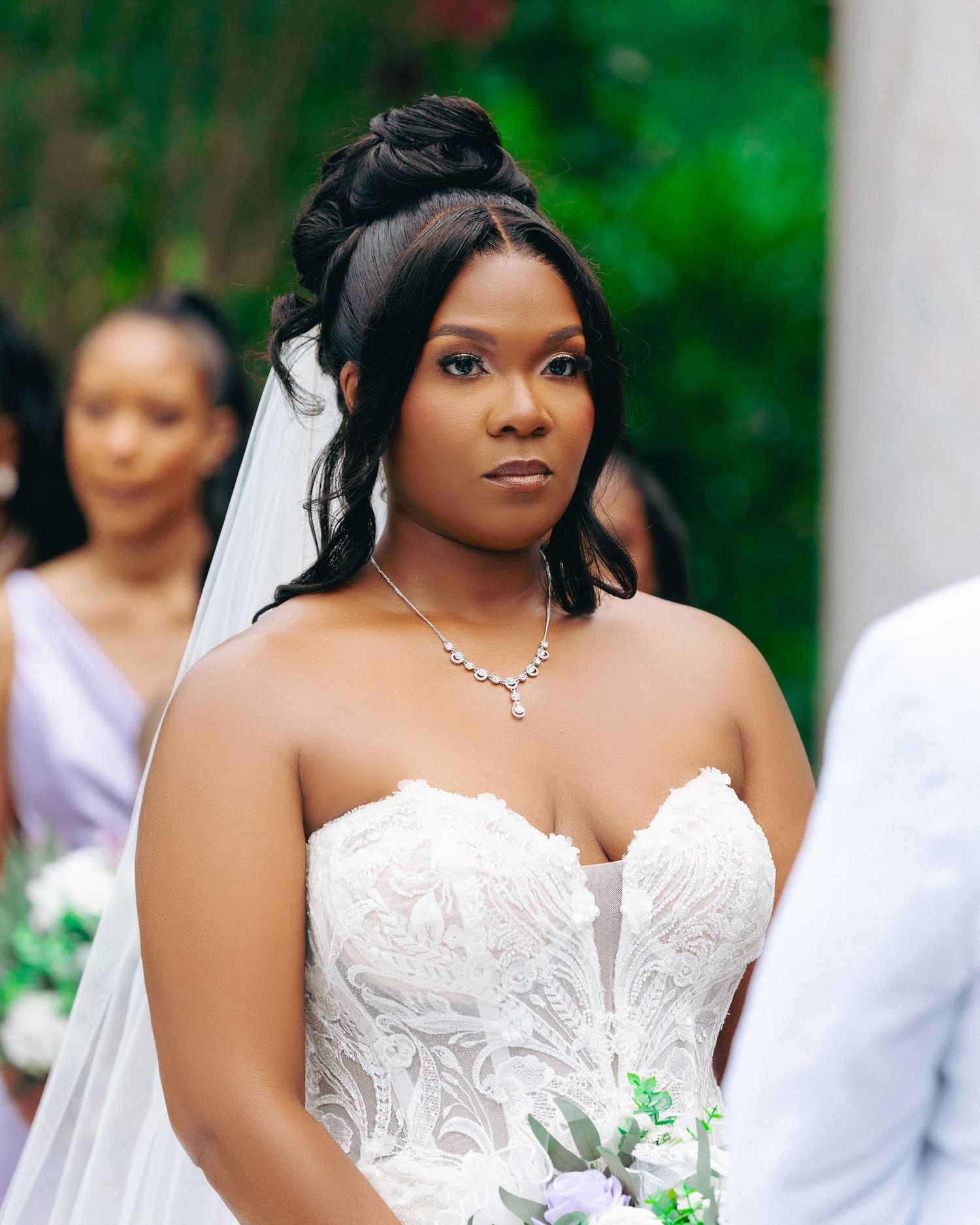 Close-up portrait of a bride in an elegant white strapless wedding gown with delicate lace details.