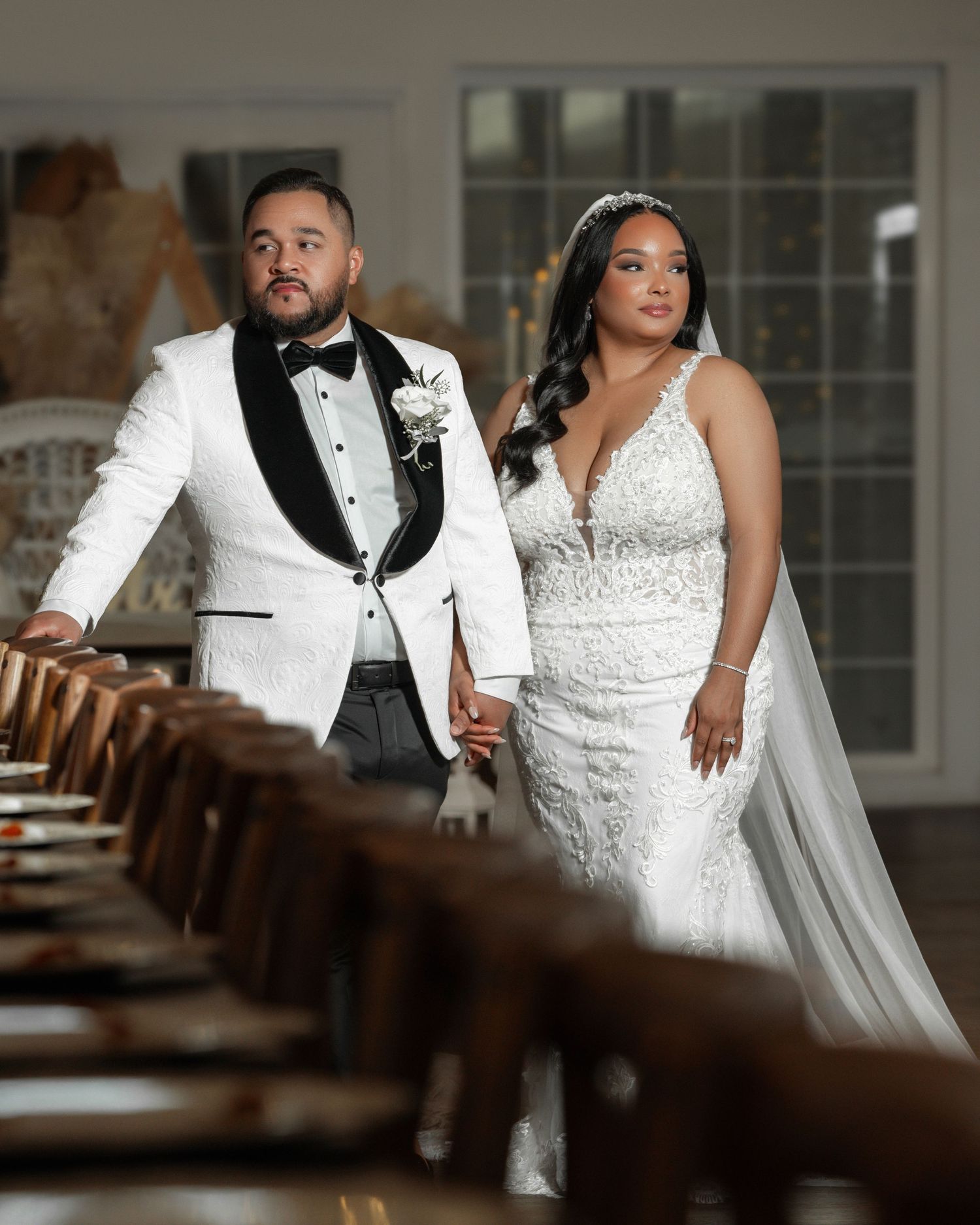 Elegant wedding couple poses in indoor venue with dramatic lighting and wooden details.