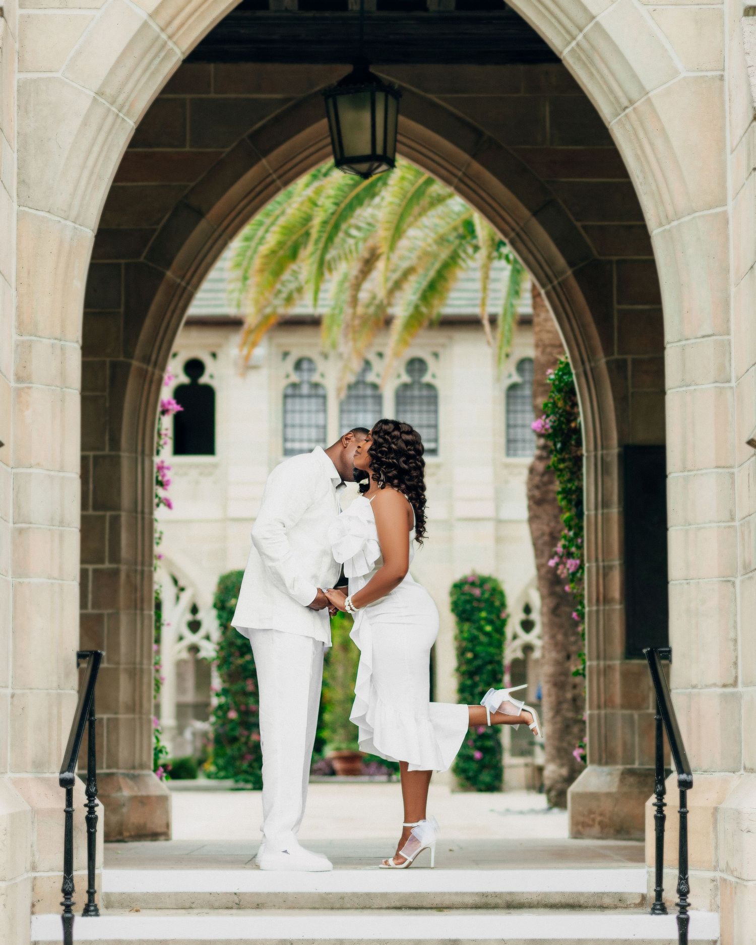 Romantic couple shares a tender moment under Gothic stone archways.