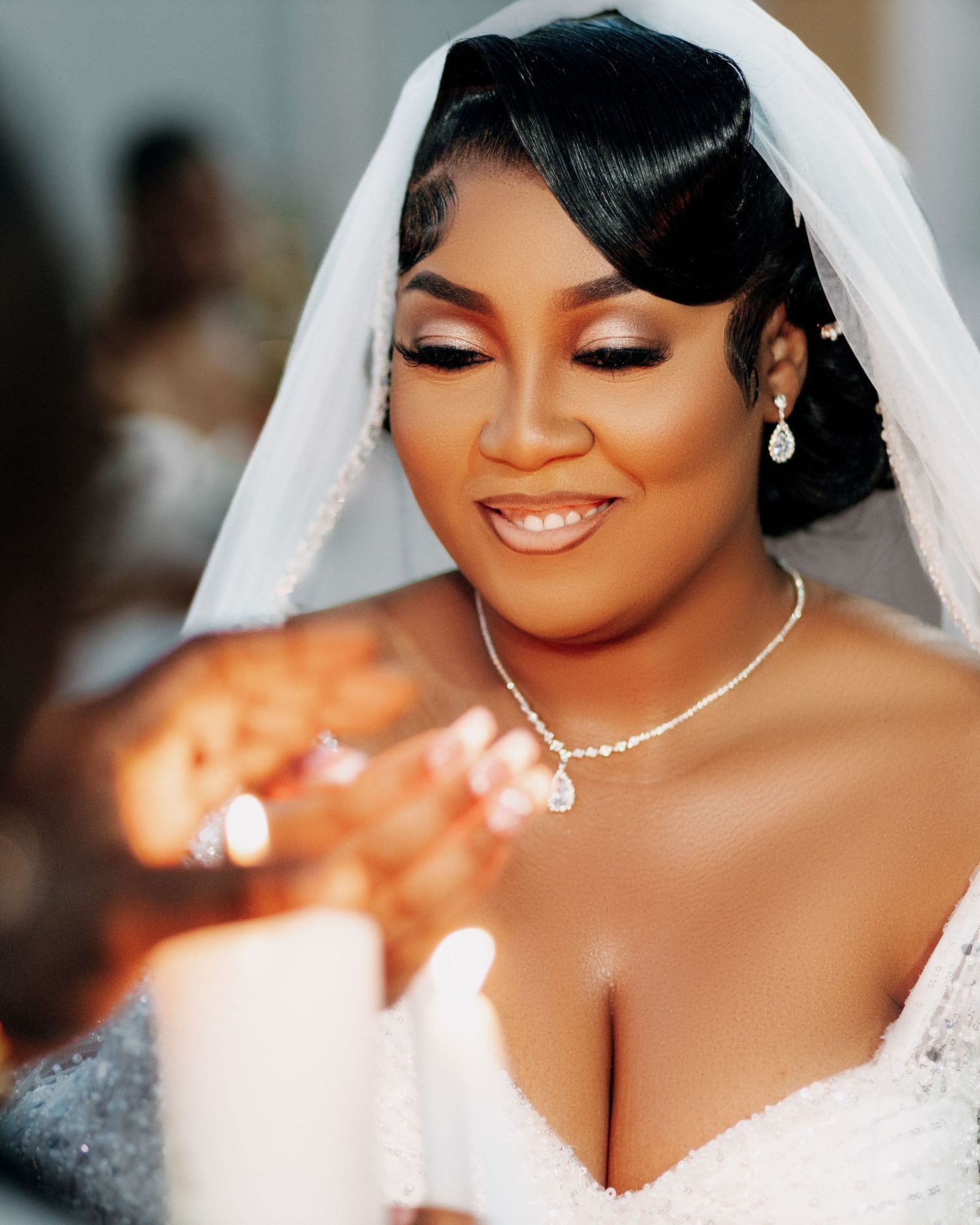 Close up portrait of a radiant bride wearing a white veil and sparkling jewelry on her wedding day.