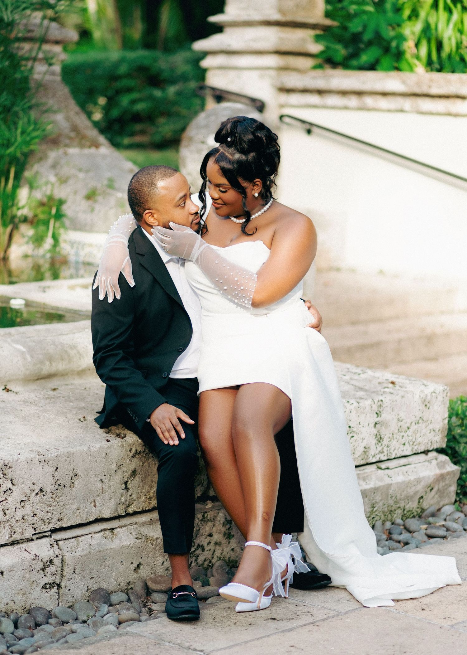 A tender moment captured between a bride in a white gown and a young child in formal attire on stone steps.