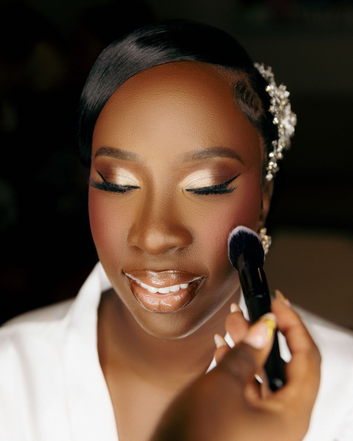 Beautiful bridal makeup application with shimmering eyeshadow, flawless skin, and delicate pearl hair accessory.