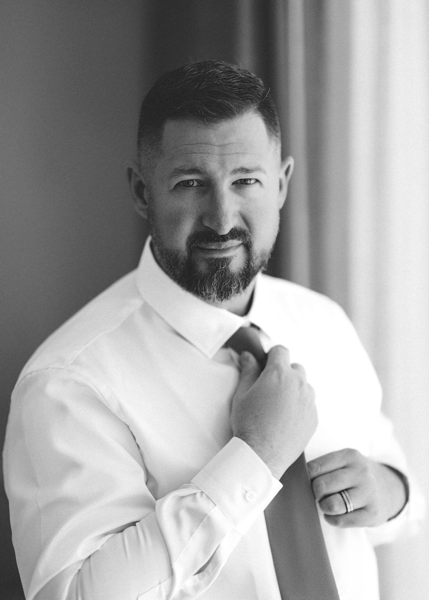 A person in a white dress shirt smiles while posing for a series of four connected portrait photographs.