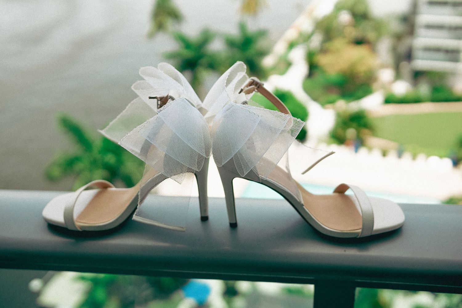 White bridal shoes and accessories arranged on a reflective surface with natural lighting.