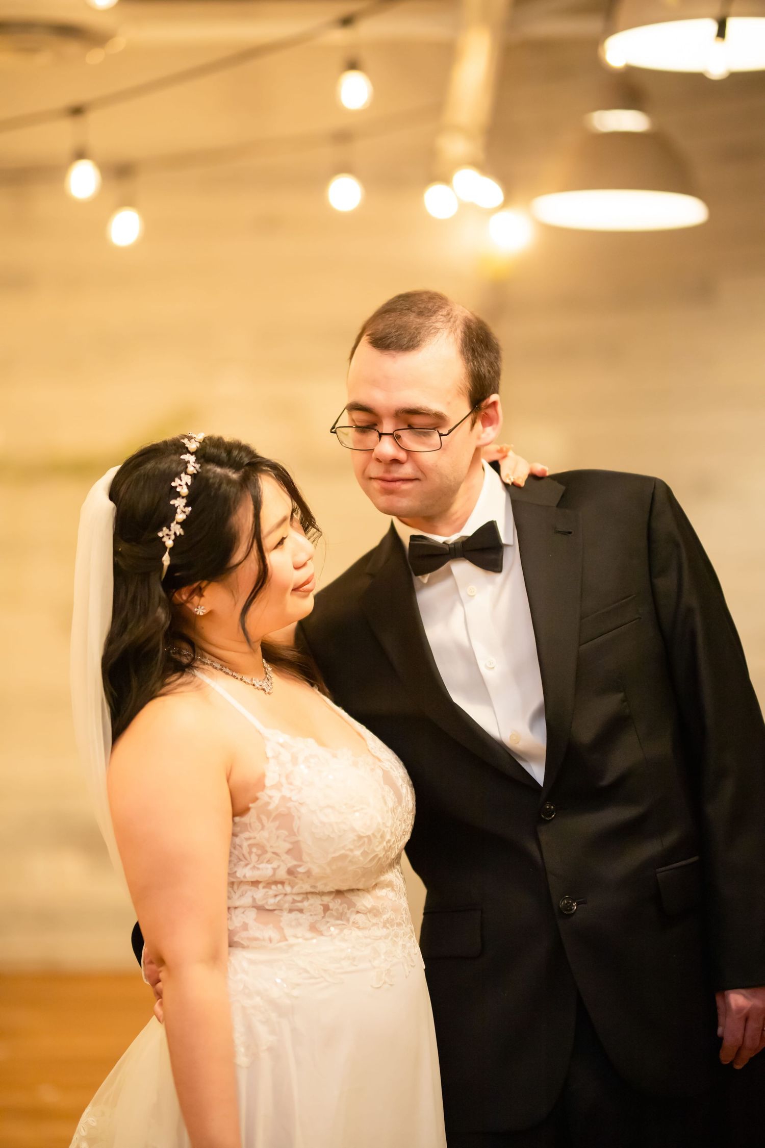 Romantic wedding moments captured under soft lighting with string lights overhead.
