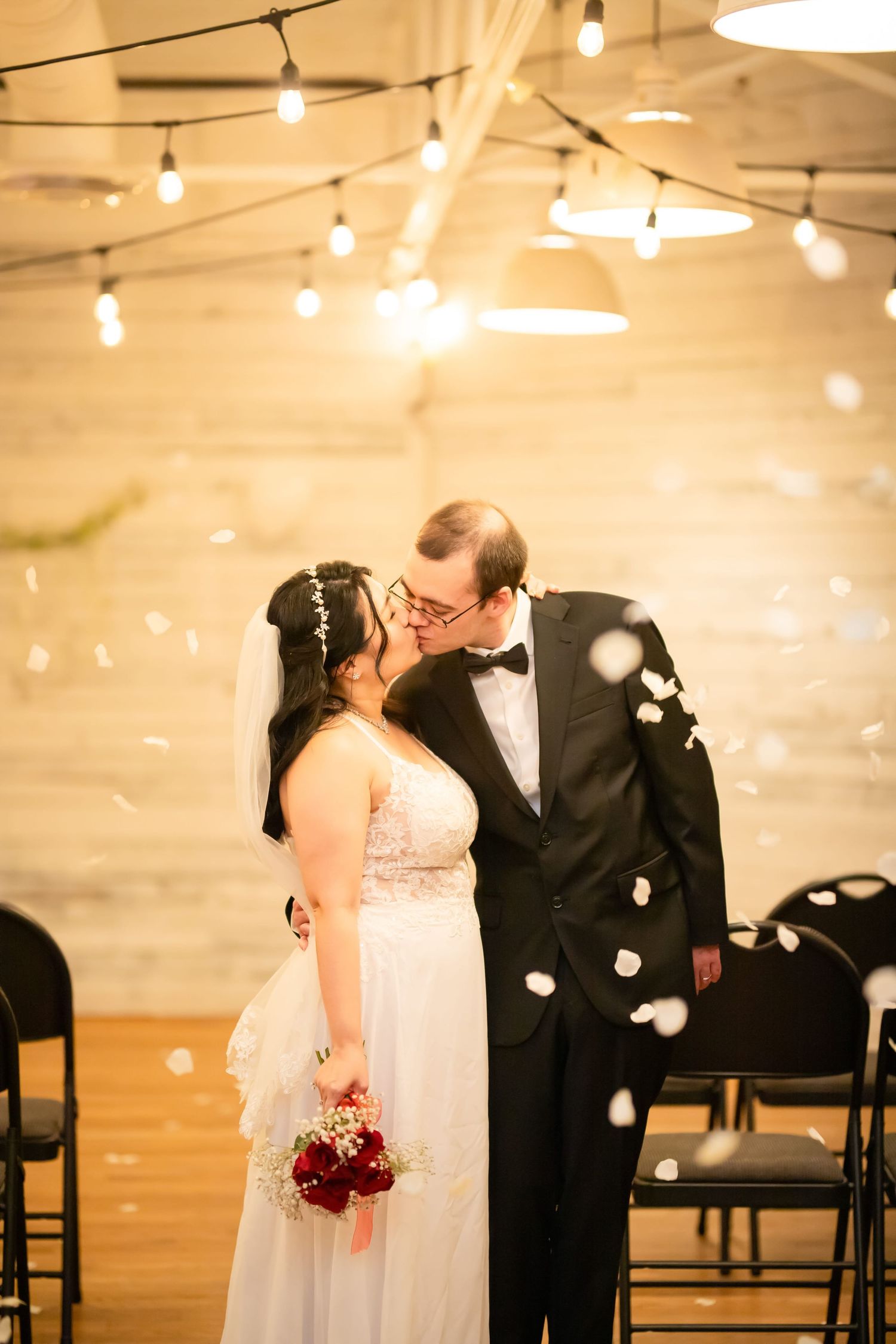 Wedding couple sharing intimate moments under warm string lights in an indoor venue.