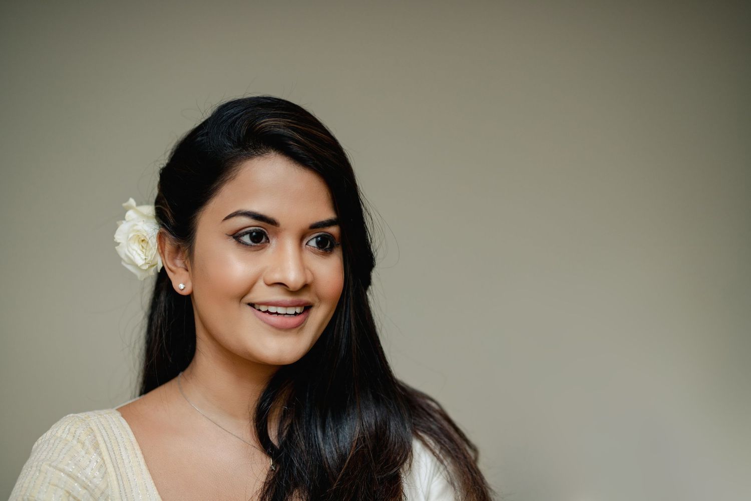 A series of portrait photos showing someone with long dark hair and white flowers against a gray background.