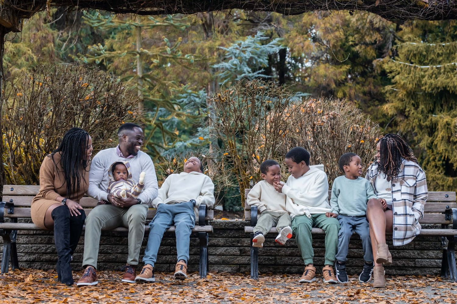 Group sitting on wooden bench in park during autumn photo session.