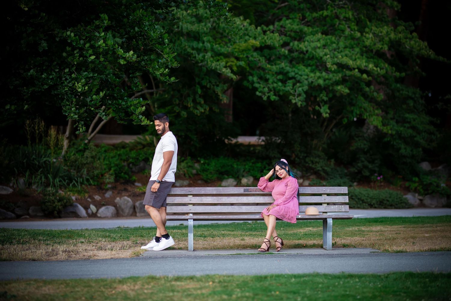 A couple relaxes together on park benches during a sunny afternoon.