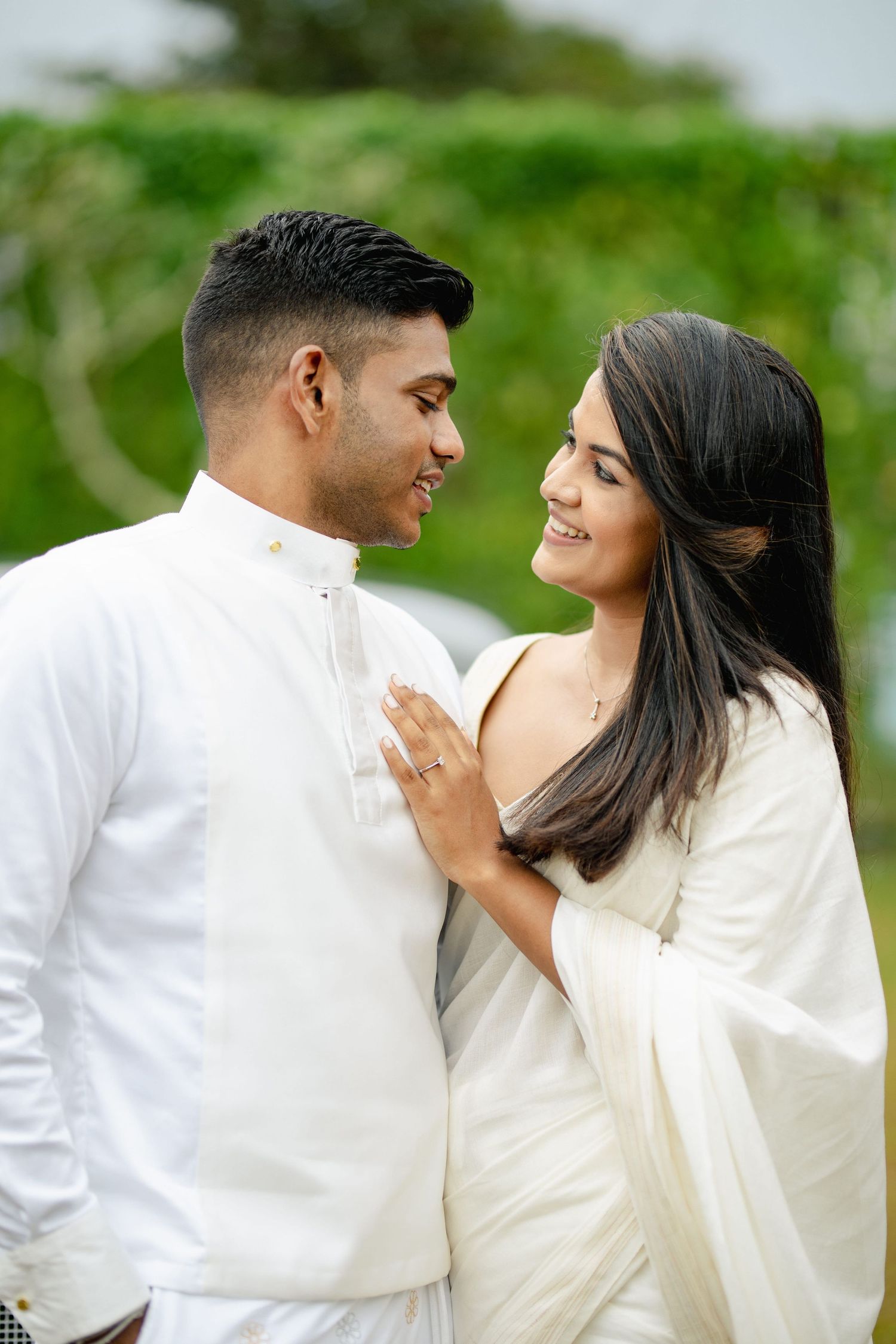 Romantic couple in white outfits sharing a tender moment outdoors.