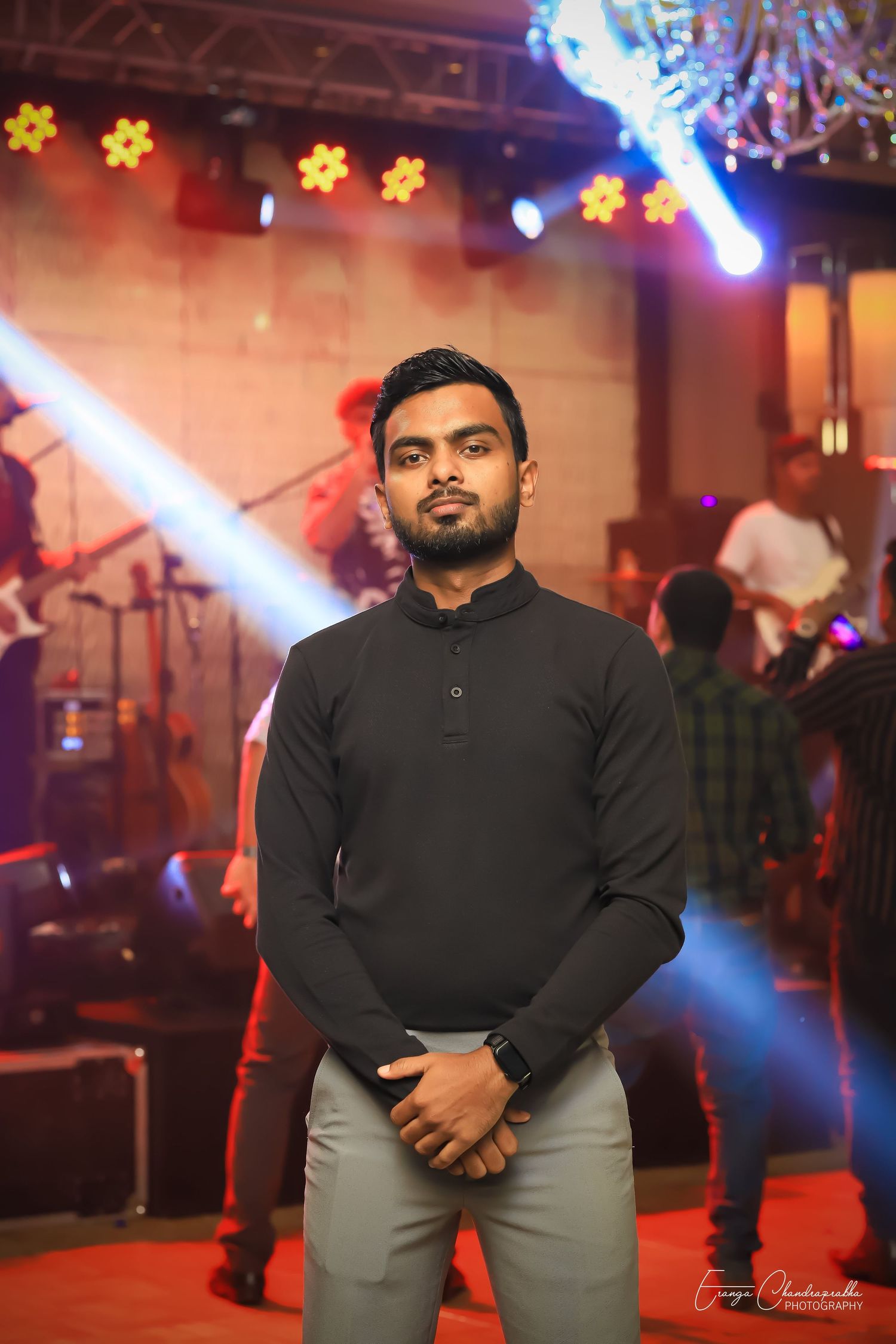 Event photography in concert venue with colorful stage lighting and floral decorations.