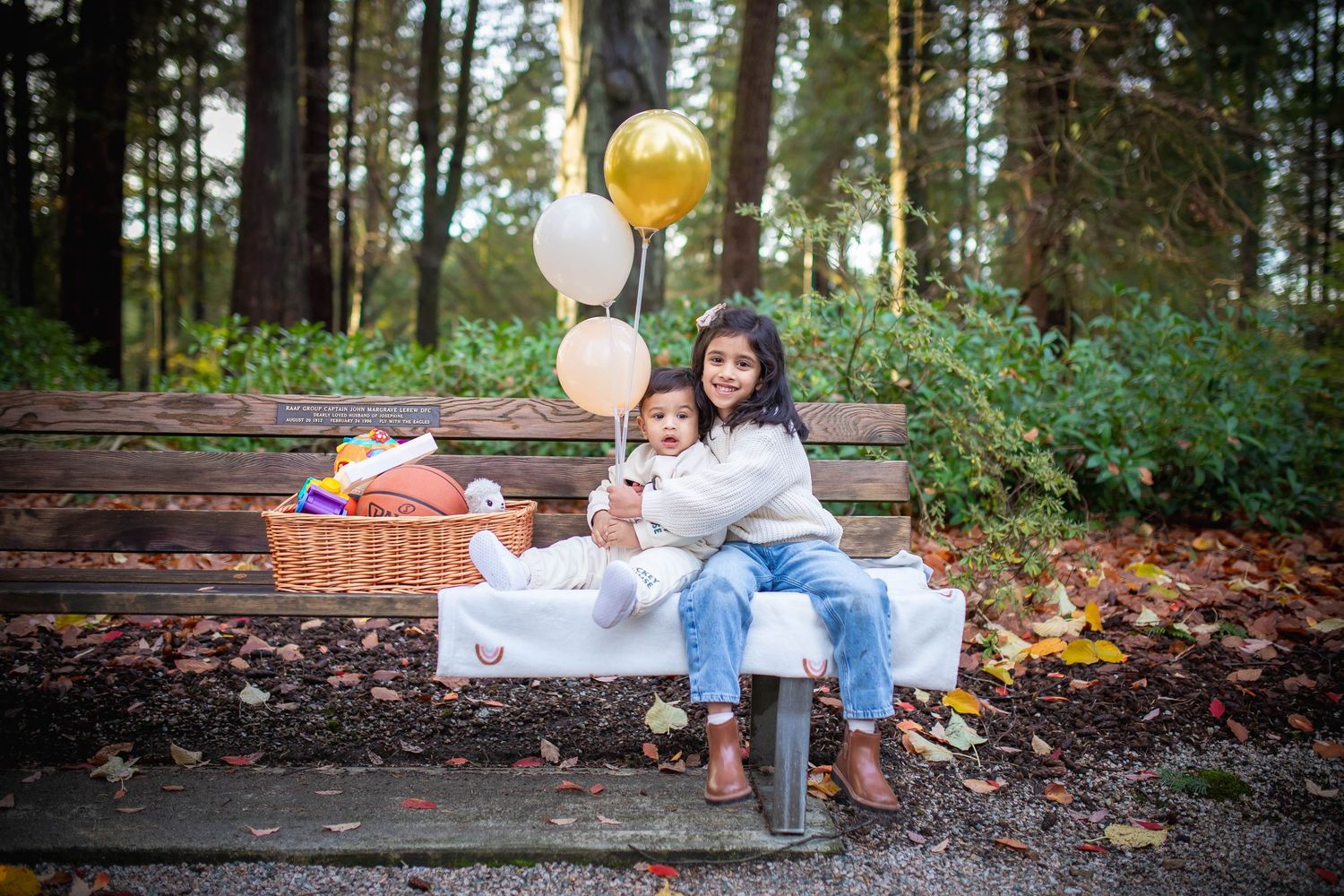 Family photo session in a wooded park setting with fall foliage and natural lighting.