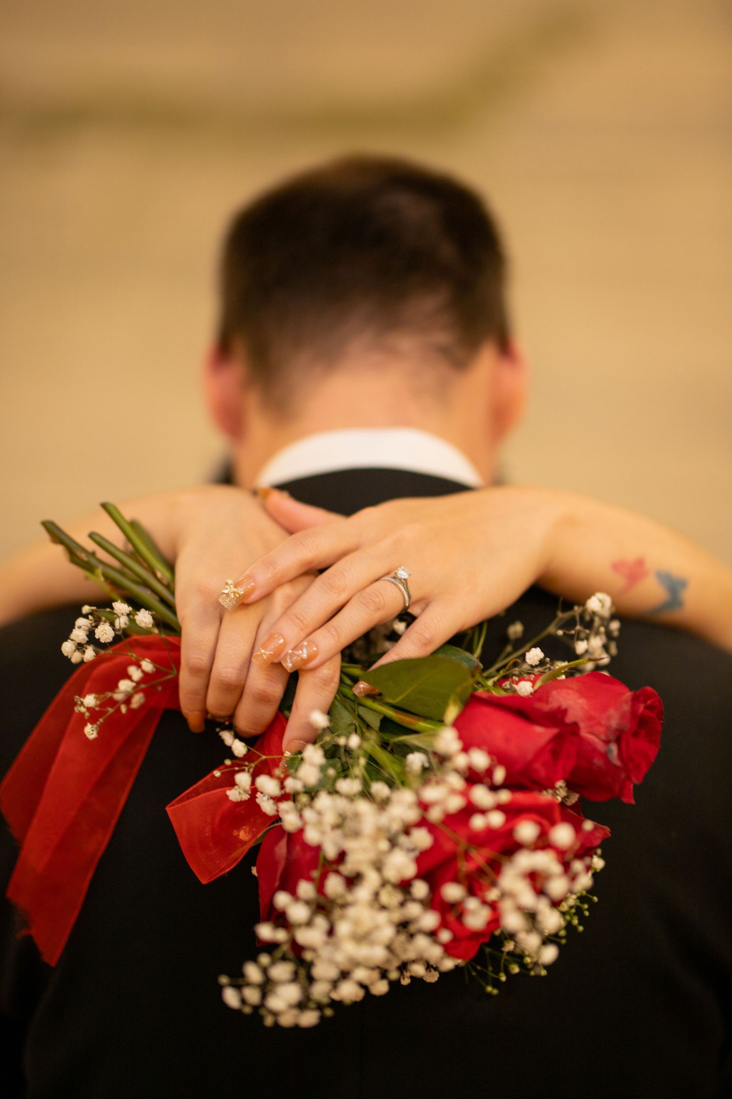 A sequence of hands showing wedding rings with red roses and baby's breath flowers against a dark background.