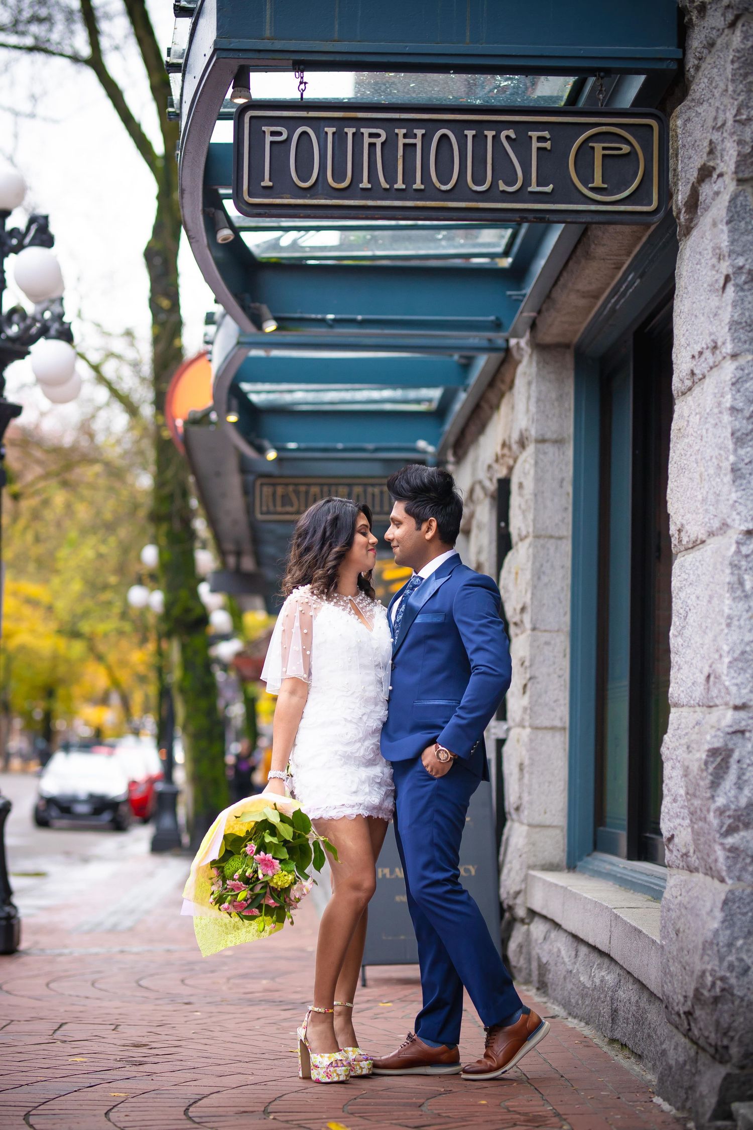 A couple shares a romantic moment outside the Fourhouse restaurant entrance on a brick sidewalk.