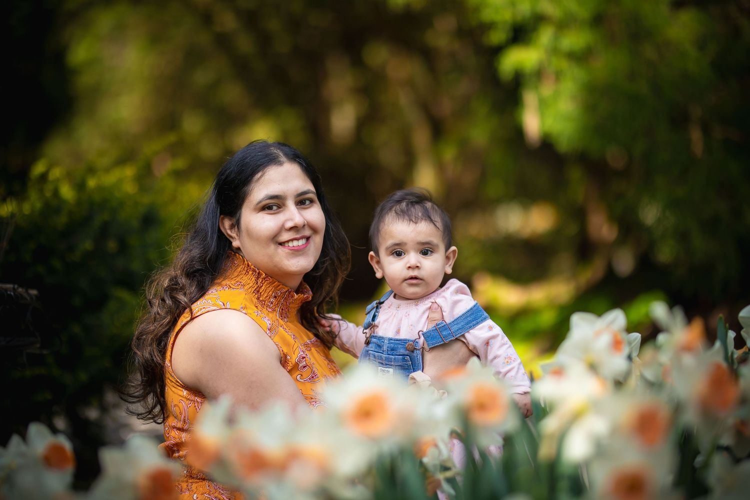 Outdoor portrait session among blooming flowers and greenery in natural setting.