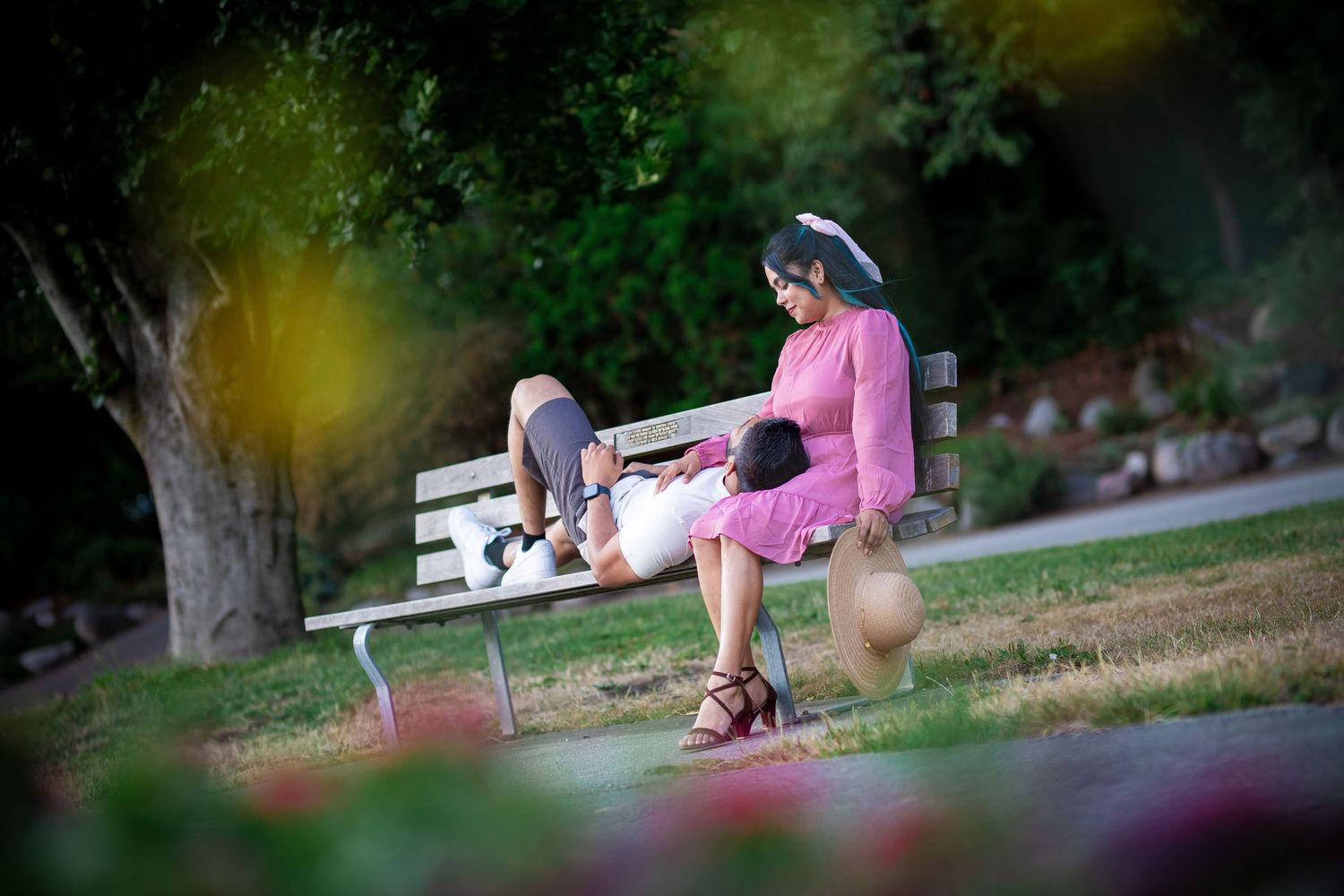 Peaceful park scene with someone in pink sitting on a bench during golden hour.