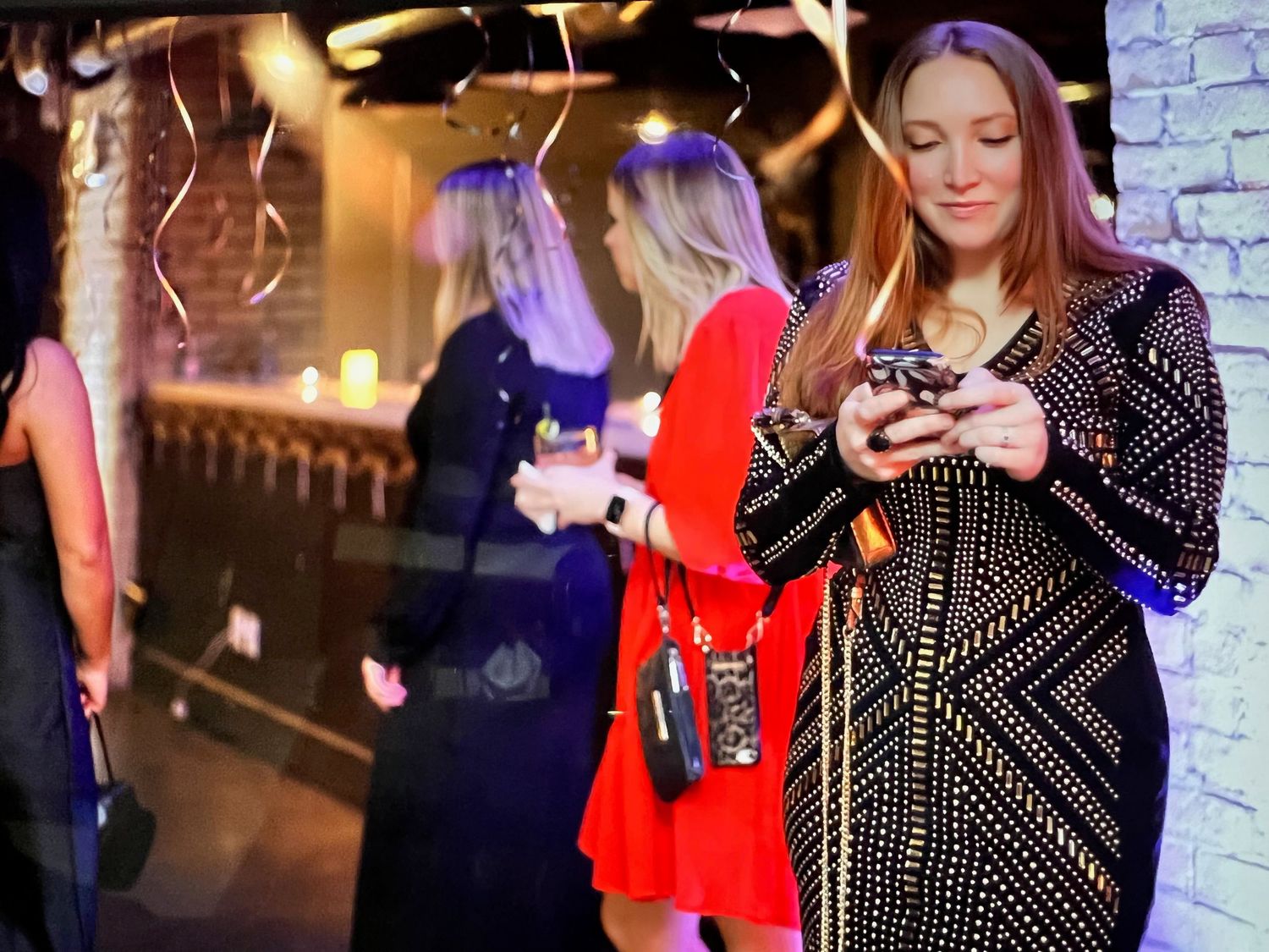 woman at a christmas event in a dress with balloons and people in the background