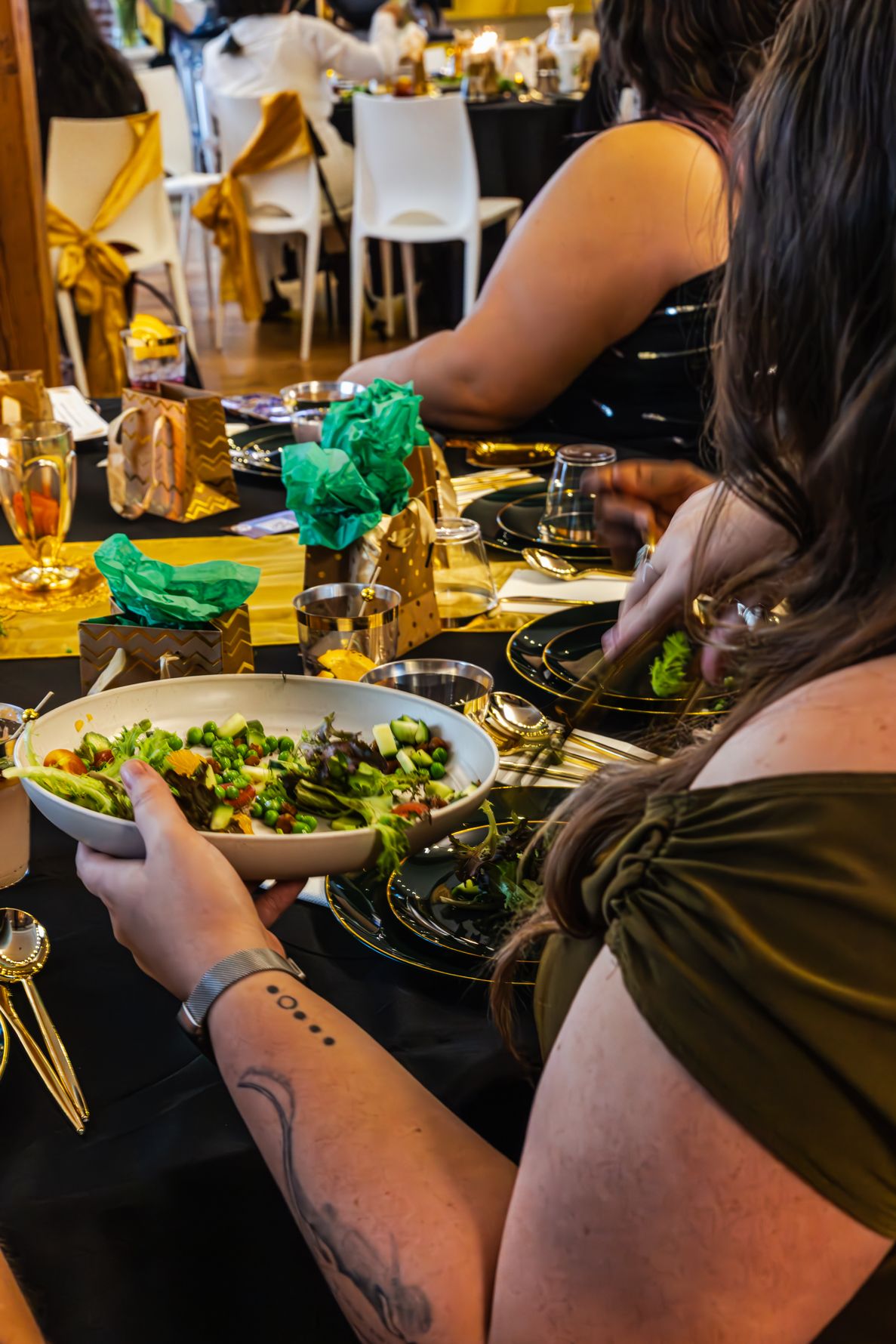 Woman serving fresh green salad at an elegant black and gold themed dinner party event. B. Steele Images. Food & Beverage photography