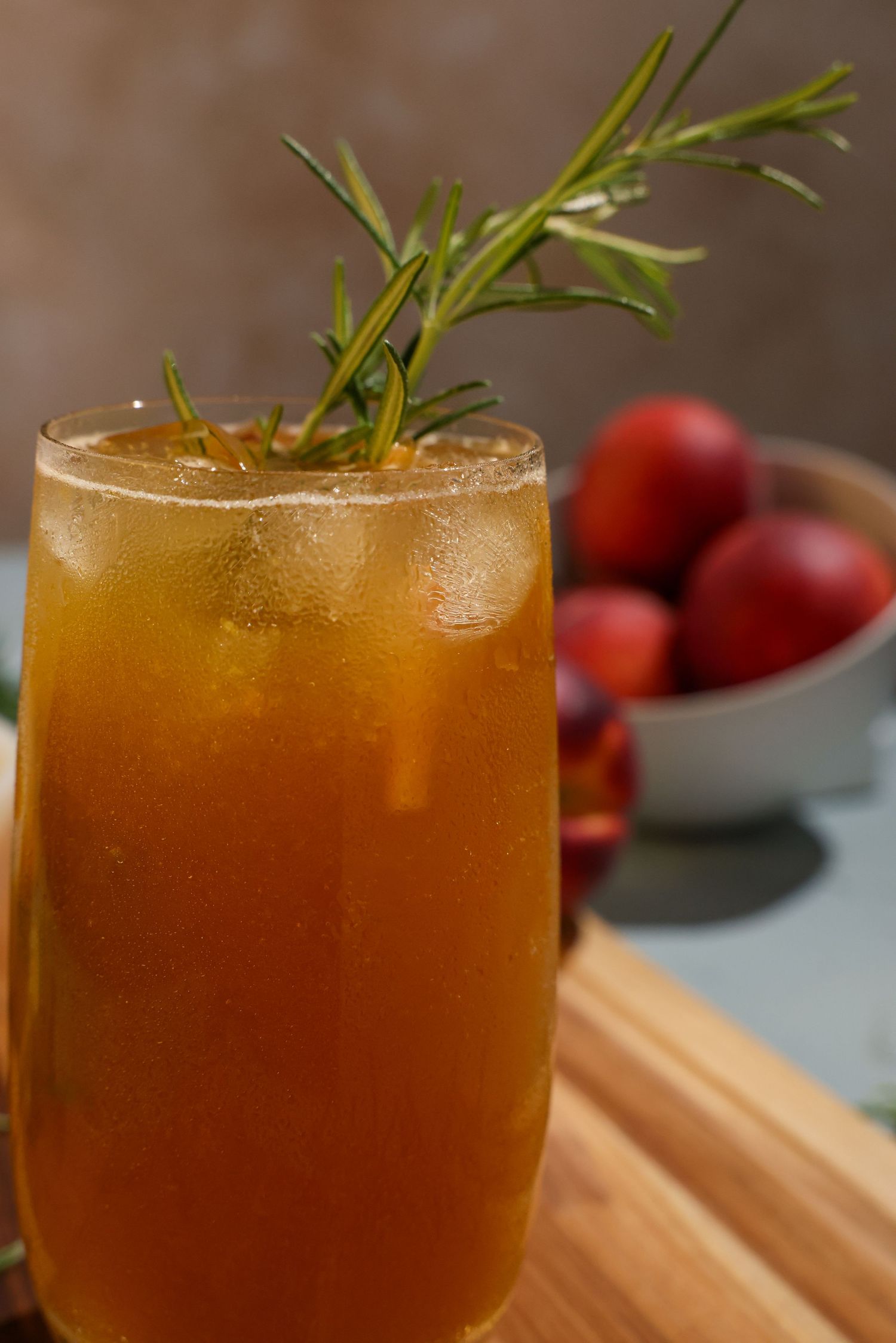 Peach Bundaberg mocktail garnished with fresh rosemary sprig served in a coupe glass on wooden surface. B. Steele Images, food photography