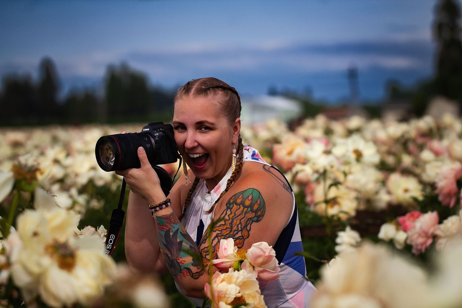 Brigit Steele, founder of B. Steele Images, indigenous photographer, crouched in a field of flowers.