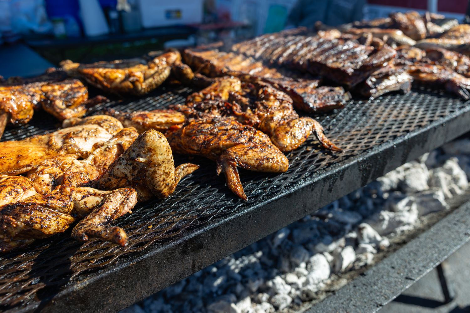 Grilled meats including chicken and ribs cooking on a large outdoor BBQ grill over hot charcoal. B. Steele Images. Food Photography