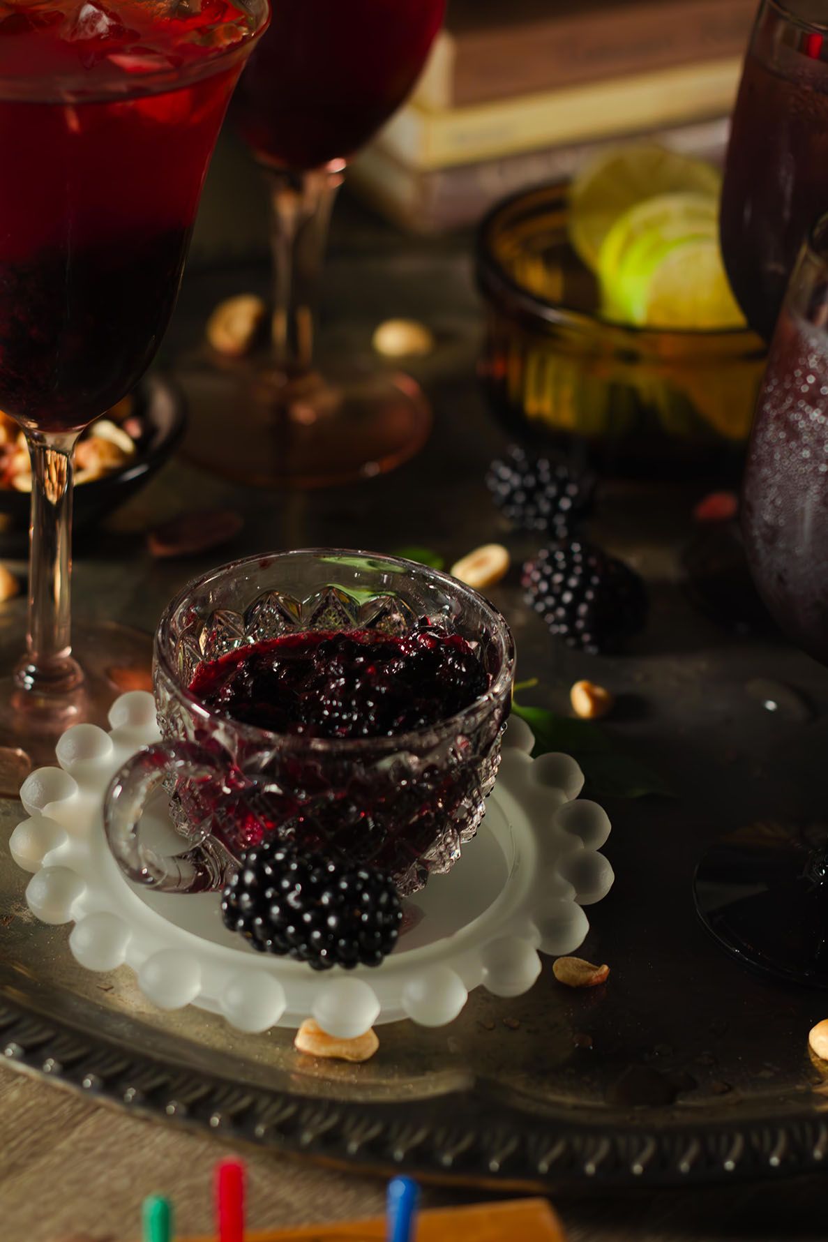 Fresh blackberries and red mocktail sangria served in elegant glassware with nuts on a dark rustic surface create an elegant setting.