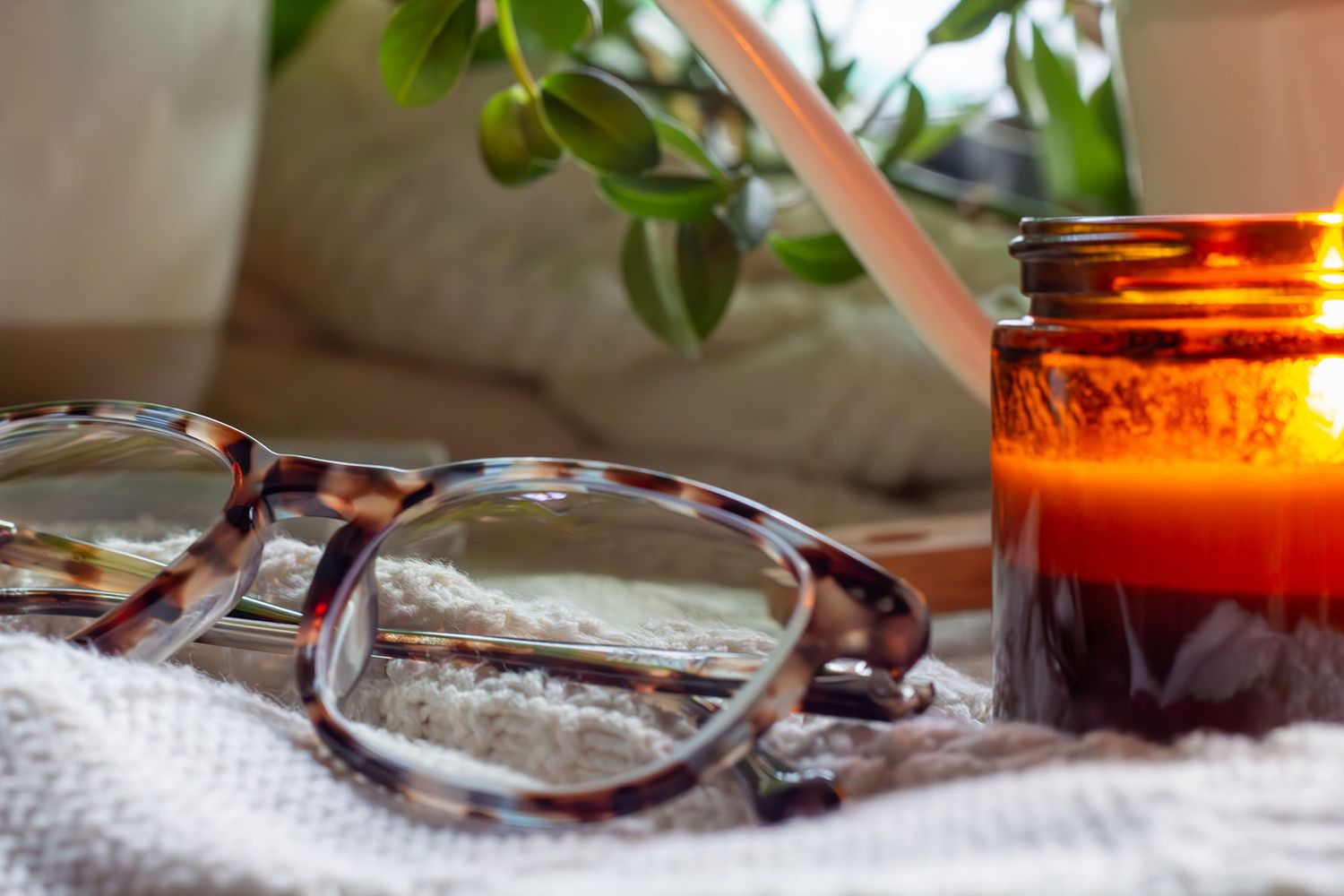 A rustic wooden table with a lit candle and decorative elements in warm, ambient lighting creates a cozy atmosphere.