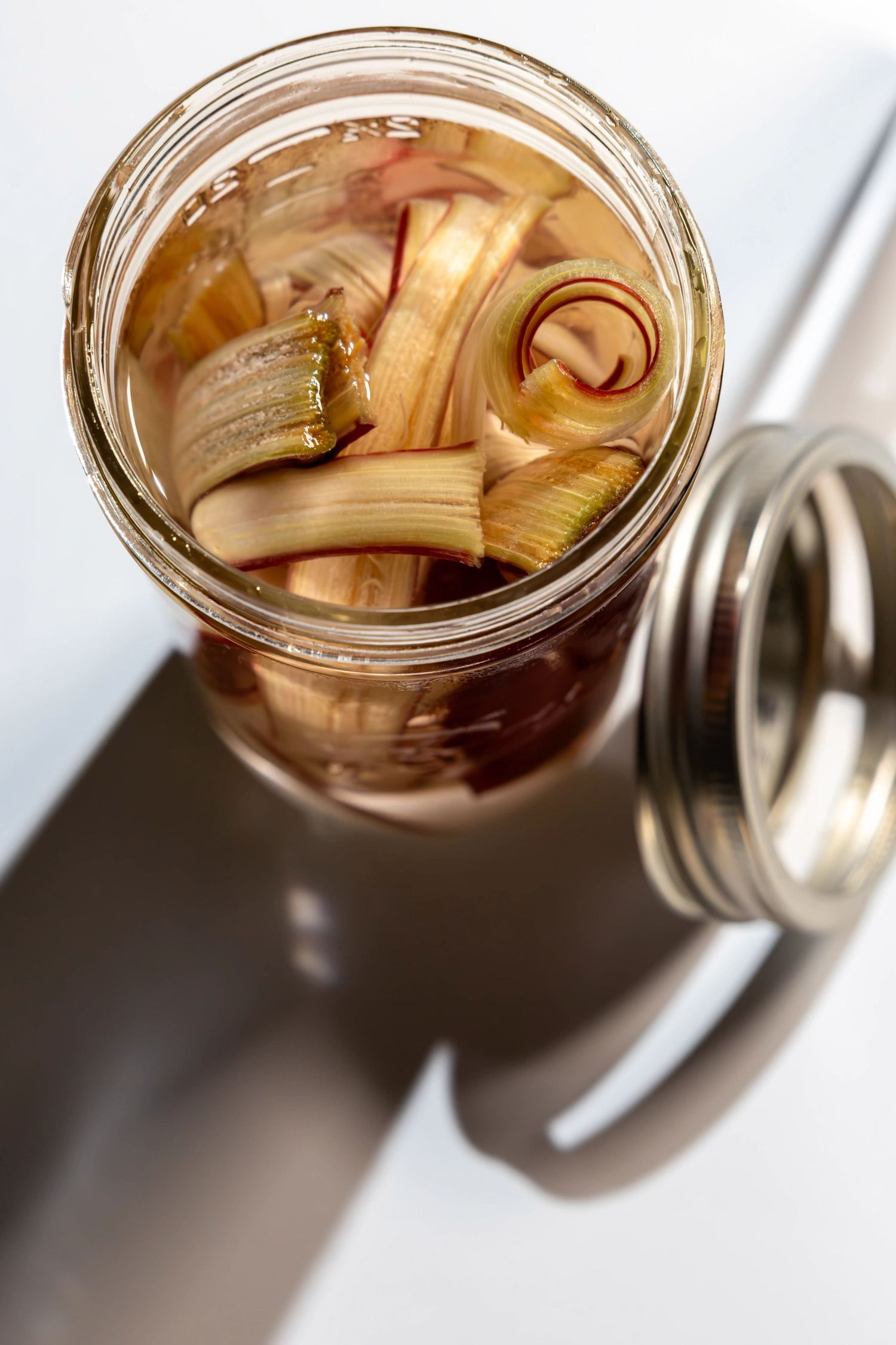 Rhubarb curls in a glass mason jar, viewed from above with lid partially visible.