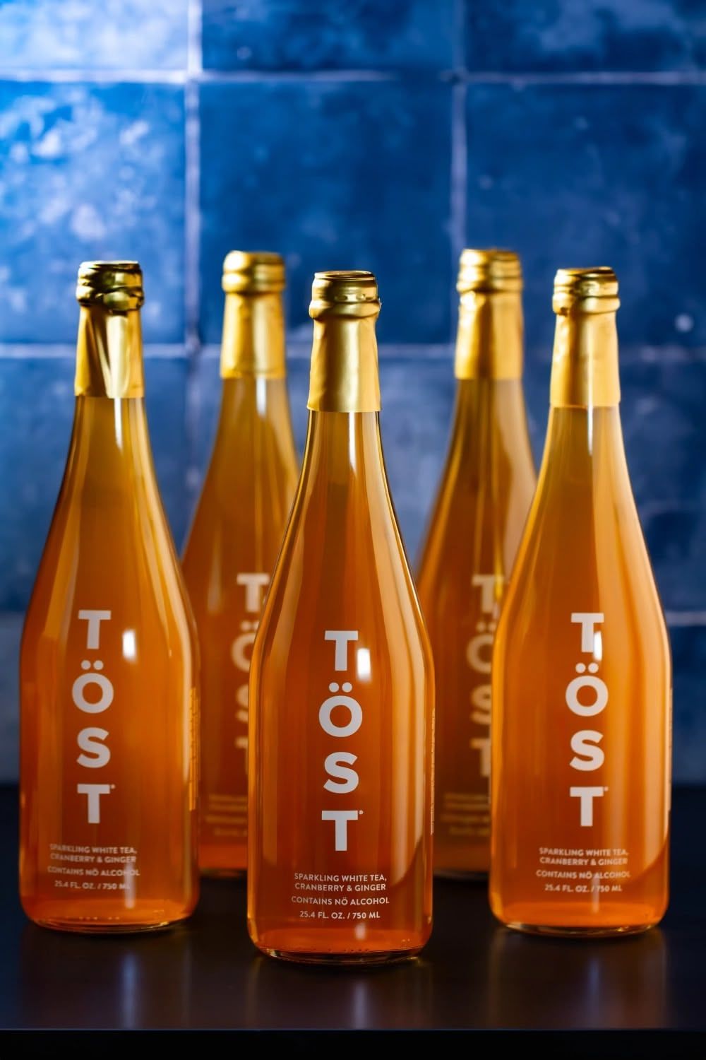 Amber glass bottles with minimalist scene Tost bottles arranged in a row against a dark blue background. Beverage styling, photography.