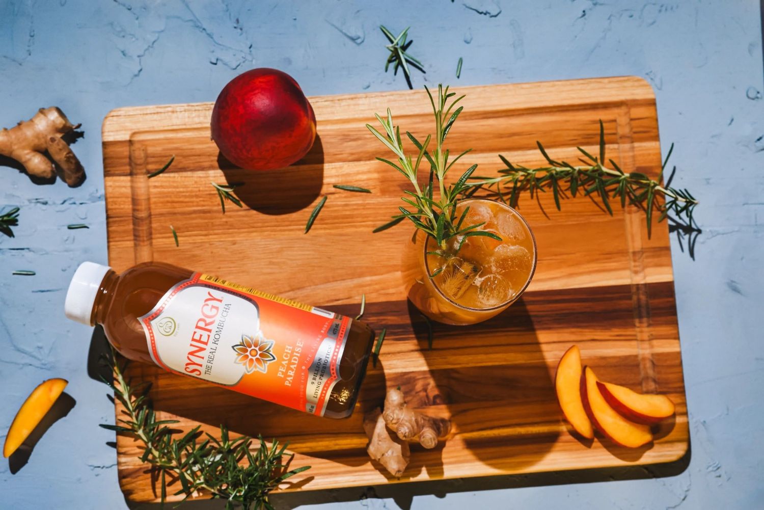 Wooden serving board, peach mocktail garnished with herbs alongside fresh fruit. B. Steele Images, Pacific Northwest product photography.