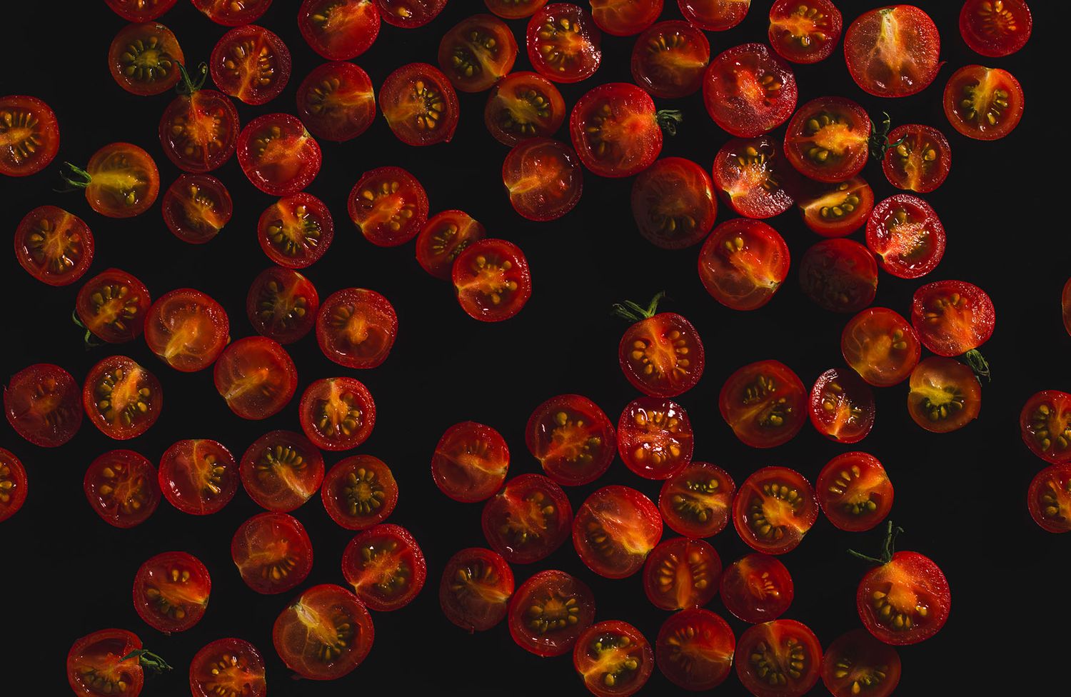 Slices of homegrown cherry tomatoes on a black background. B. Steele Images, food and beverage photography