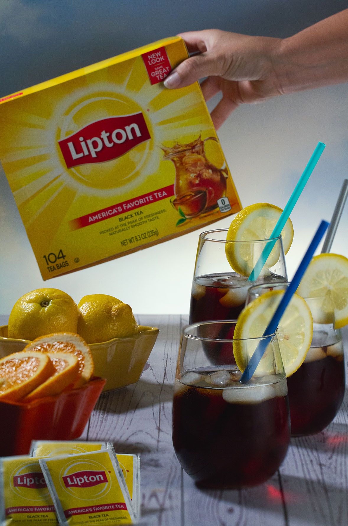 Lipton iced tea being served in glasses with lemon slices and blue straws against a white surface. B. Steele Images, food photography